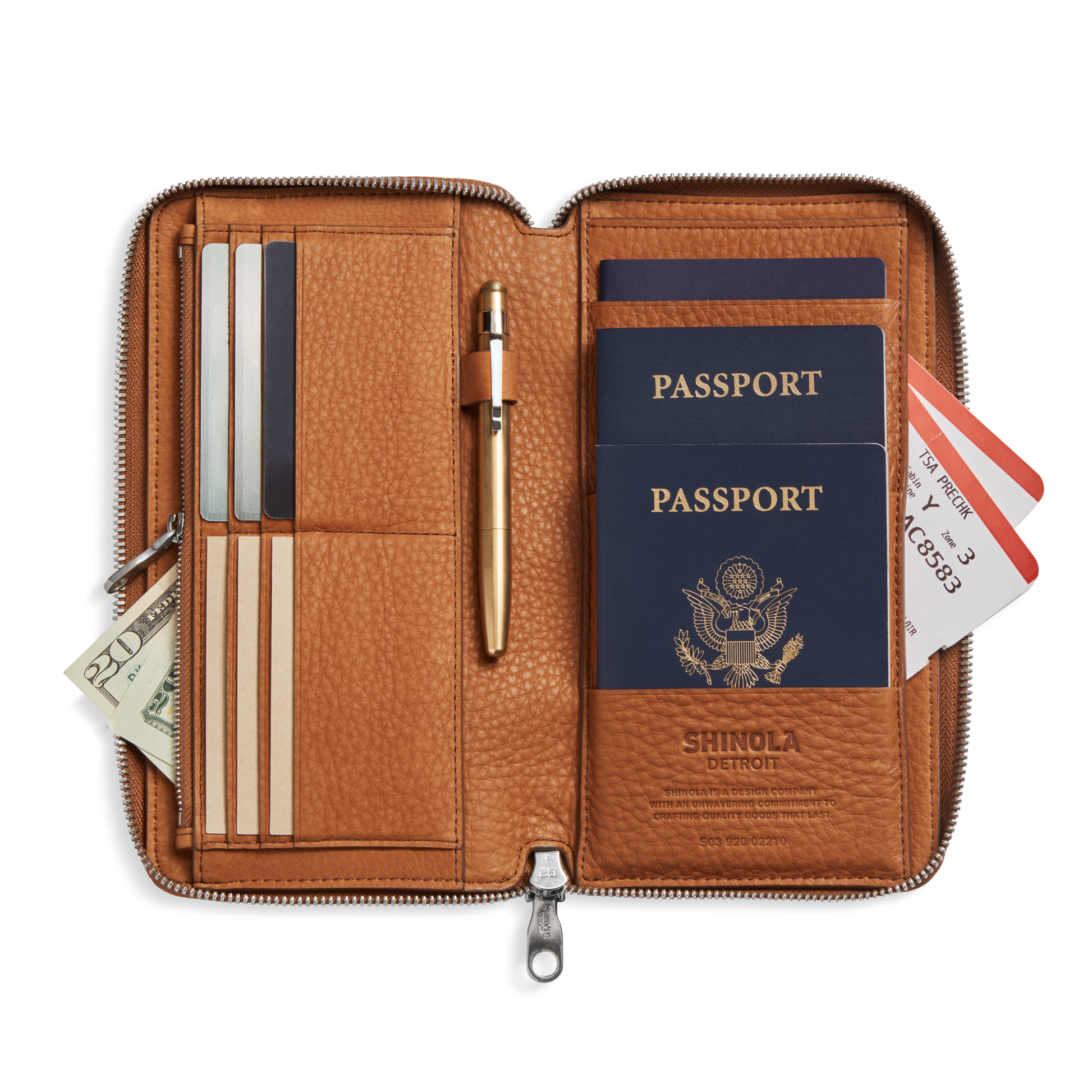 The Shinola Organizer Wallet - Tan is open, displaying two U.S. passports, a pen, cards, cash, credit cards, and boarding passes neatly organized inside this travel wallet.