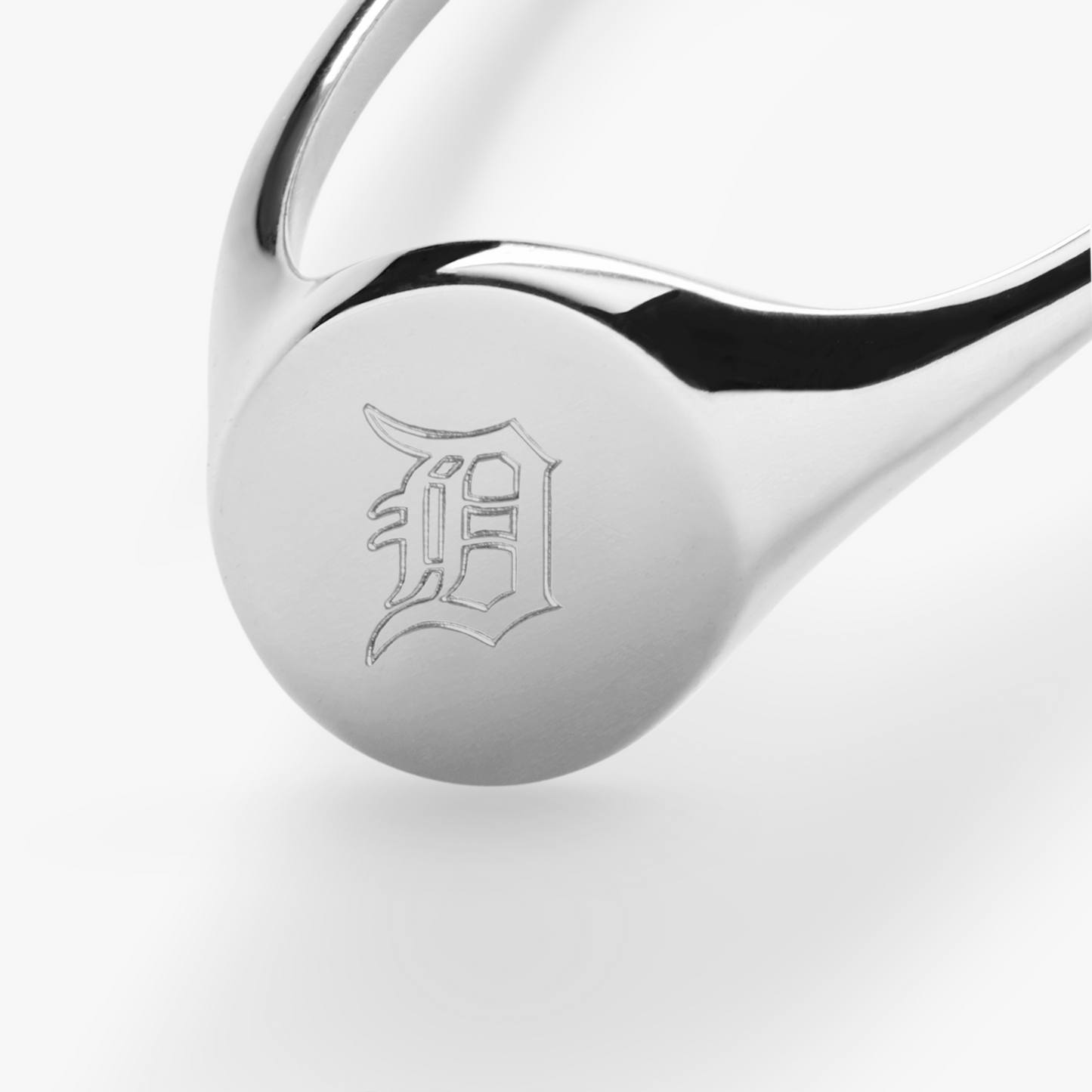 The Shinola Petite Round Signet Ring in sterling silver features a flat, round top engraved with an ornate, gothic-style letter D on a white background for timeless style.