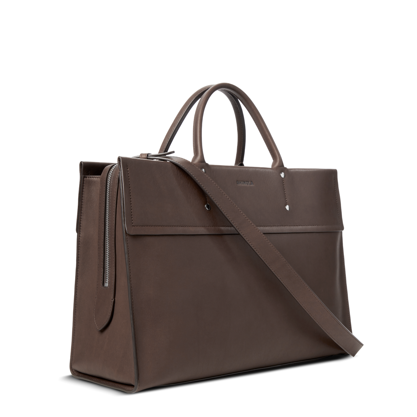 The Shinola Day Satchel - Espresso is a brown leather tote with top handles, a detachable shoulder strap, subtle branding on the front flap, and a silver side zipper detail, all set against a white background.