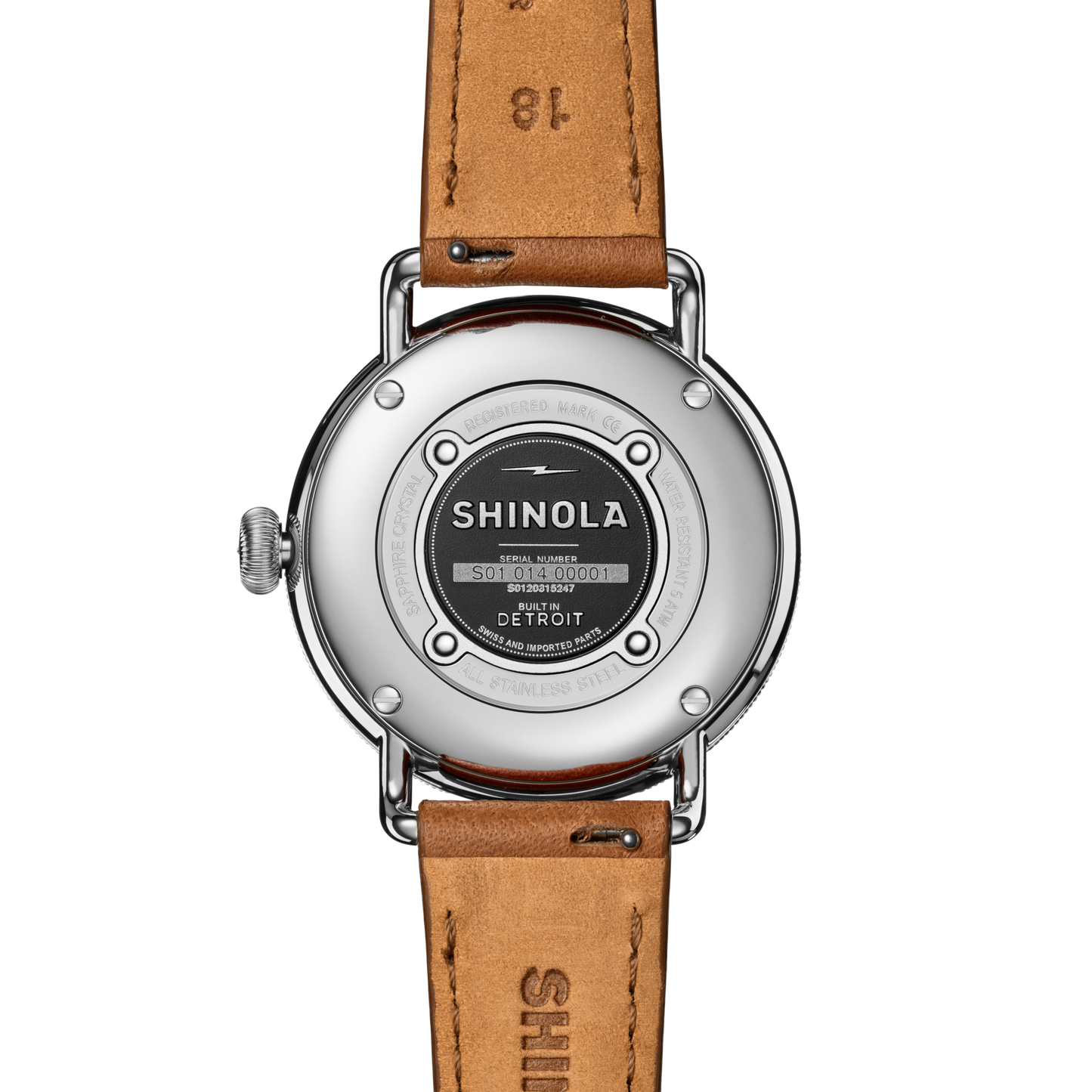 The back of the Shinola Canfield Watch features a round stainless steel case, engraved details, and a tan leather strap. The case displays the brand name, serial number, "Built in Detroit," and notes its precise Argonite 705 movement.