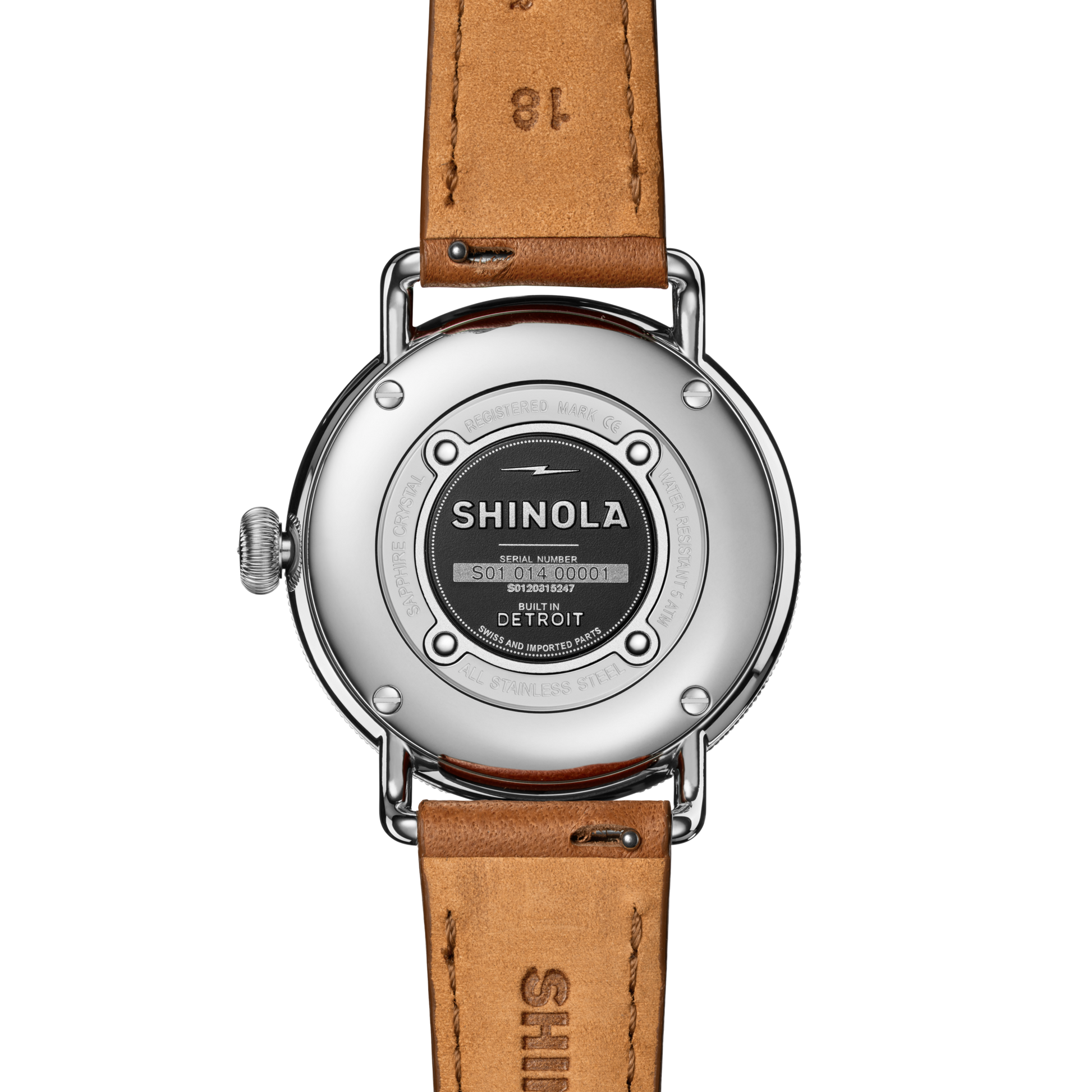 The back of the Shinola Canfield Watch features a round stainless steel case, engraved details, and a tan leather strap. The case displays the brand name, serial number, "Built in Detroit," and notes its precise Argonite 705 movement.