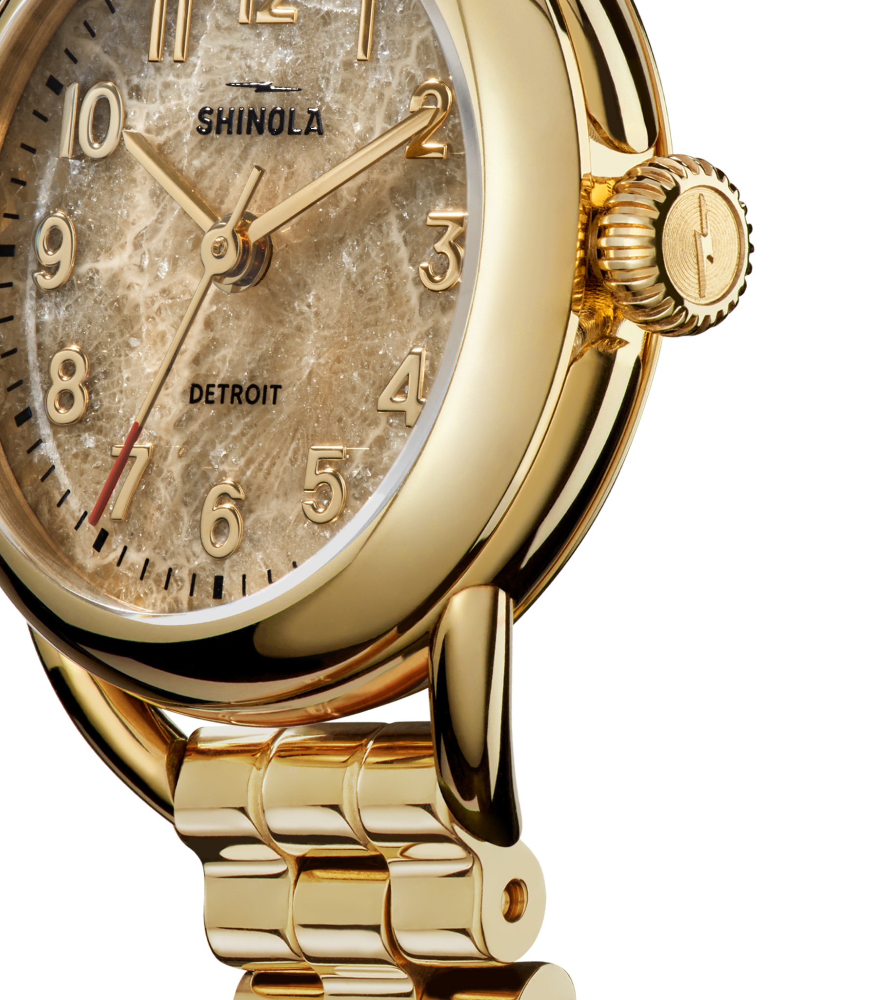 Close-up of a gold Shinola Runabout Watch - Petoskey with a textured beige face, gold hour markers and hands. The words 'Shinola' and 'Detroit' appear on the Detroit-assembled watch. Gold-colored metallic band is visible.