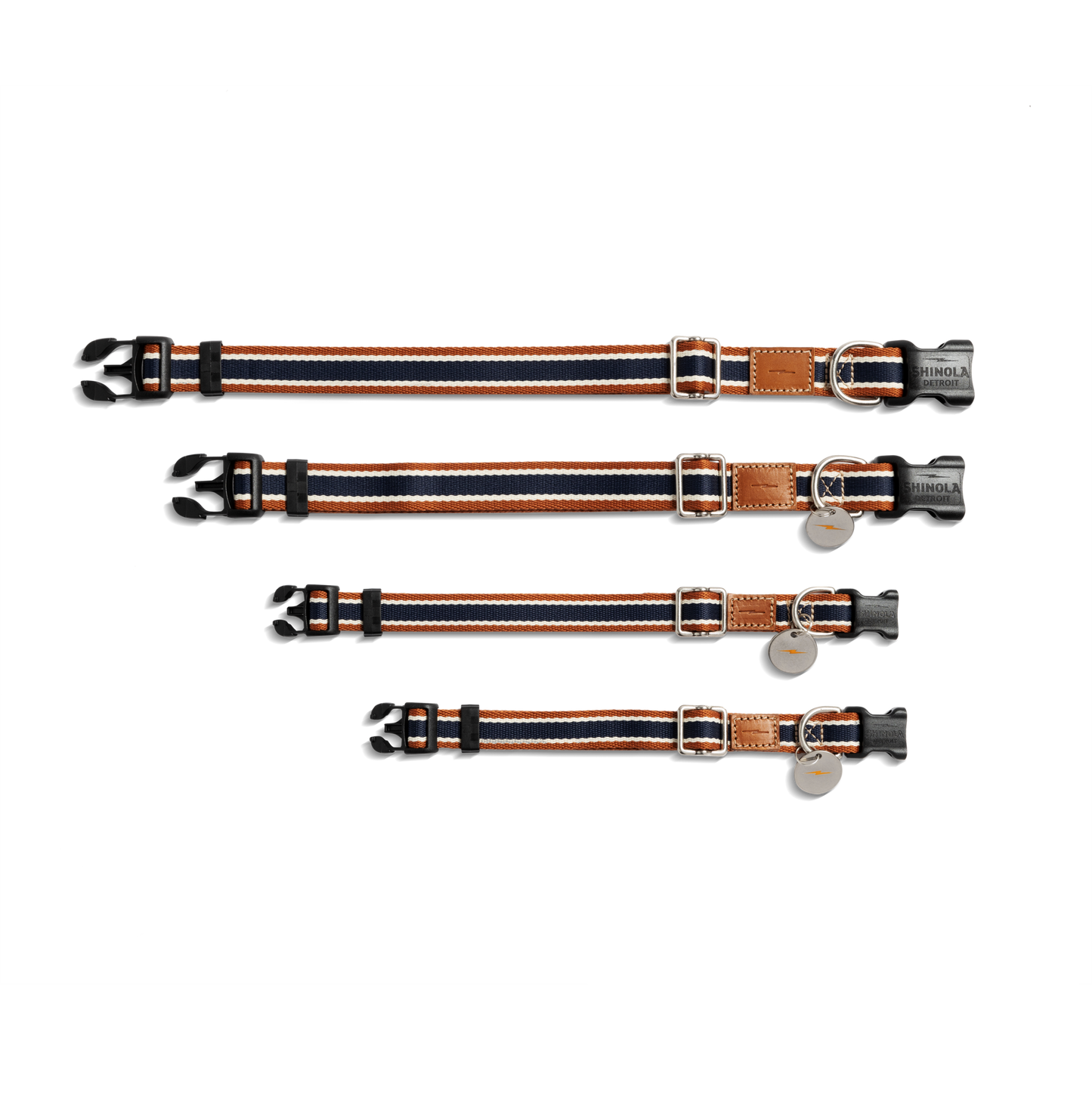 Four Shinola Nylon Dog Collar - Brand Stripe collars in different sizes, each with black, orange, and white stripes, black plastic buckles, silver rings, and a brown leather patch are laid parallel on a white background.