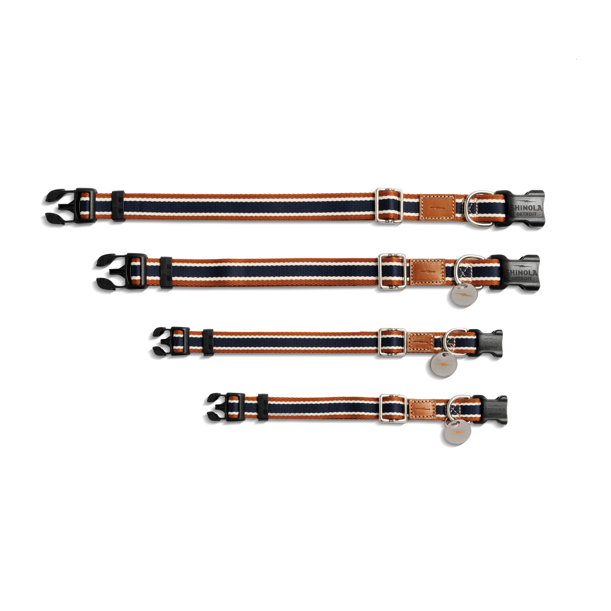 Four Shinola Nylon Dog Collar - Brand Stripe collars in different sizes, each with black, orange, and white stripes, black plastic buckles, silver rings, and a brown leather patch are laid parallel on a white background.