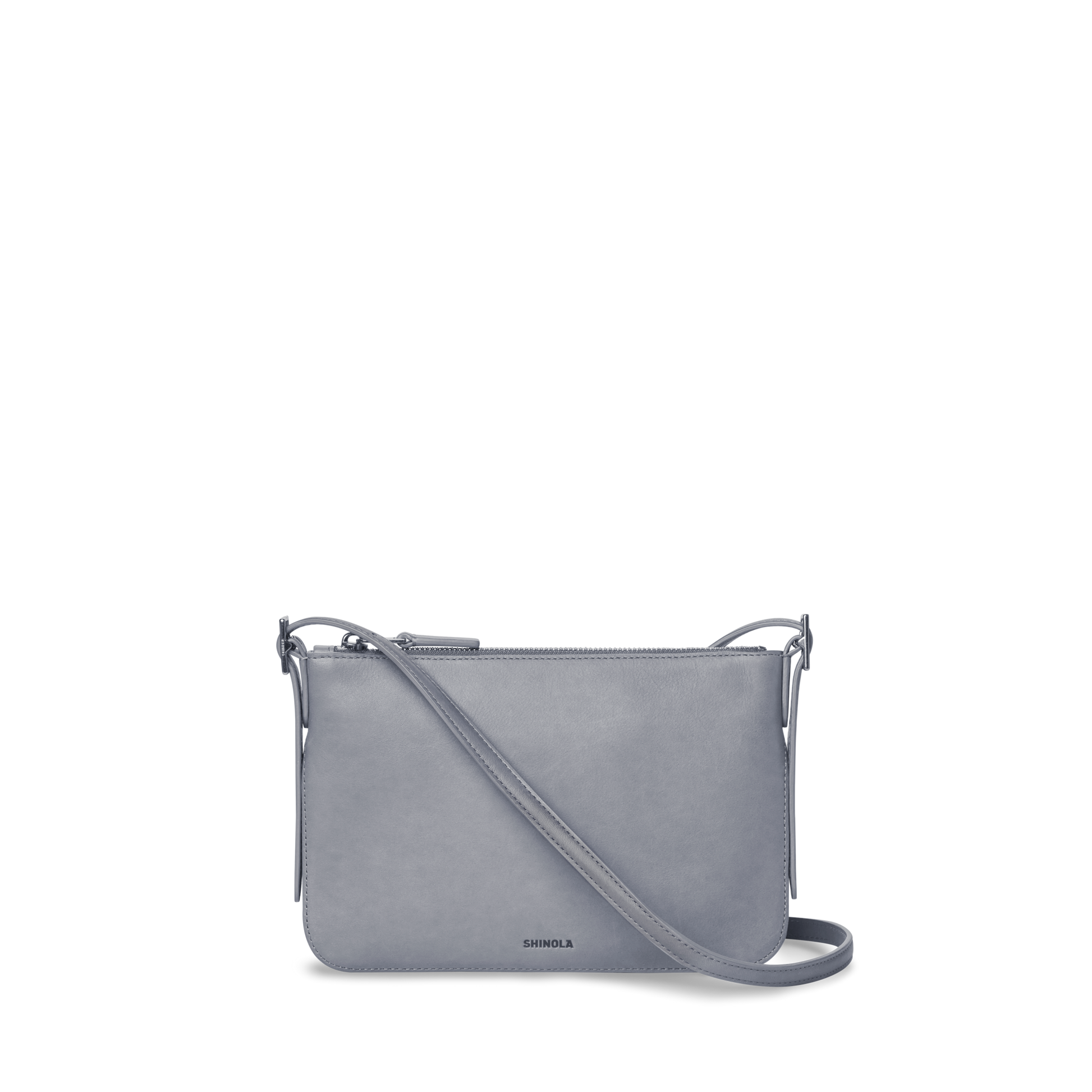 The Small Bixby Crossbody - Mist by Shinola is a sleek, light gray Natural Leather bag with a rectangular shape, adjustable strap, top zipper closure, and subtle branding—perfect for everyday use.