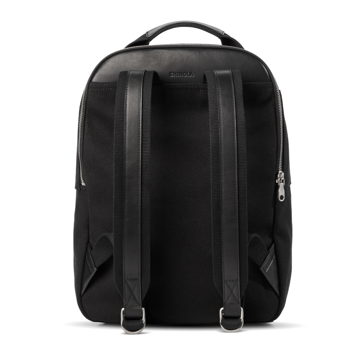 The Shinola Runwell Canvas Backpack in black is shown from the back, featuring leather accents, adjustable padded straps, metal buckles, a top handle, and visible side zippers—ideal for everyday use or adventure.