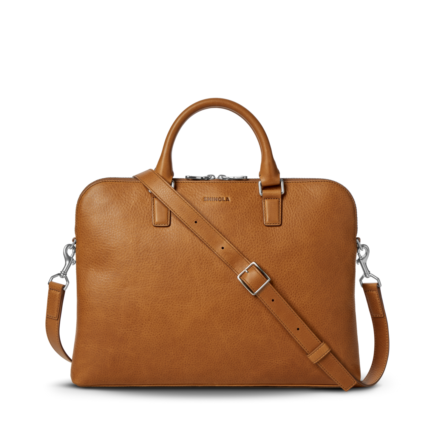 The Portfolio Briefcase - Tan by Shinola features top handles, a detachable shoulder strap, silver hardware, and an embossed logo on tan European leather. This slim laptop briefcase is showcased against a plain white background.
