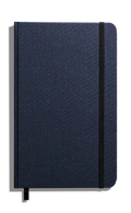 The Shinola Medium Hard Ruled Journal in navy features a closed hard linen cover, black elastic band at the right edge, and a purple ribbon bookmark visible at the bottom, displayed on a white background.