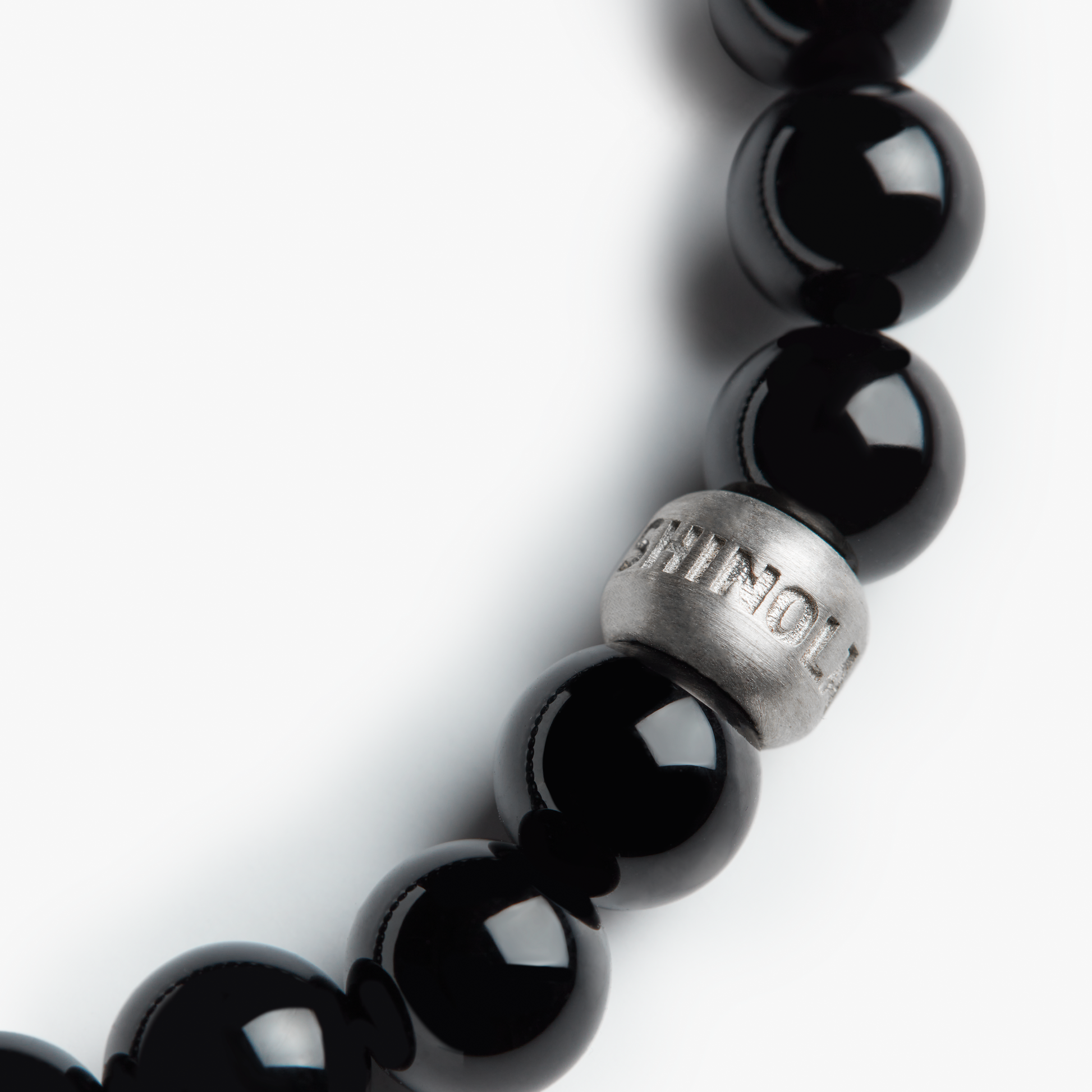 A close-up of the Shinola 8mm Beaded Onyx Bracelet, featuring an Onyx stone and a sterling silver accent bead engraved with the Shinola logo, set against a white background.