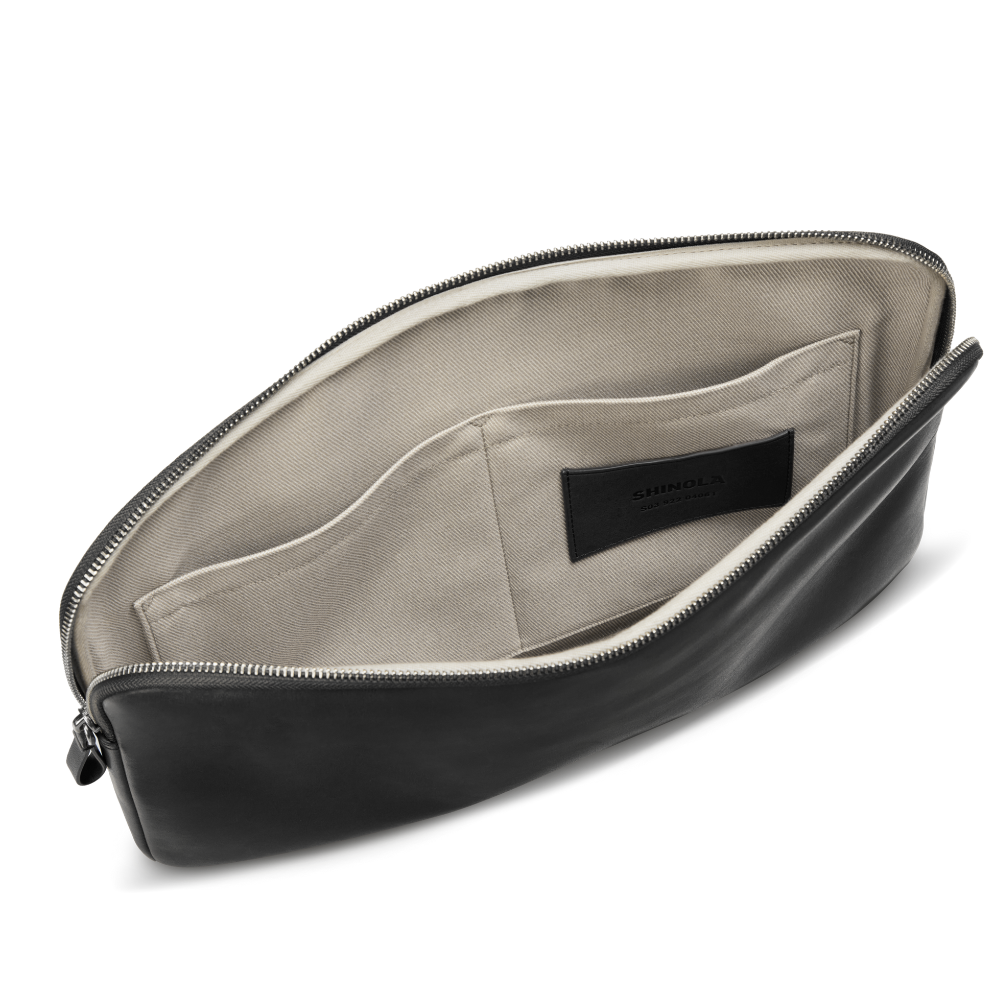 The Shinola Laptop Tech Case - Black, shown open, features a light beige fabric interior with two inner pockets and a black label inside—perfect for organizing accessories.