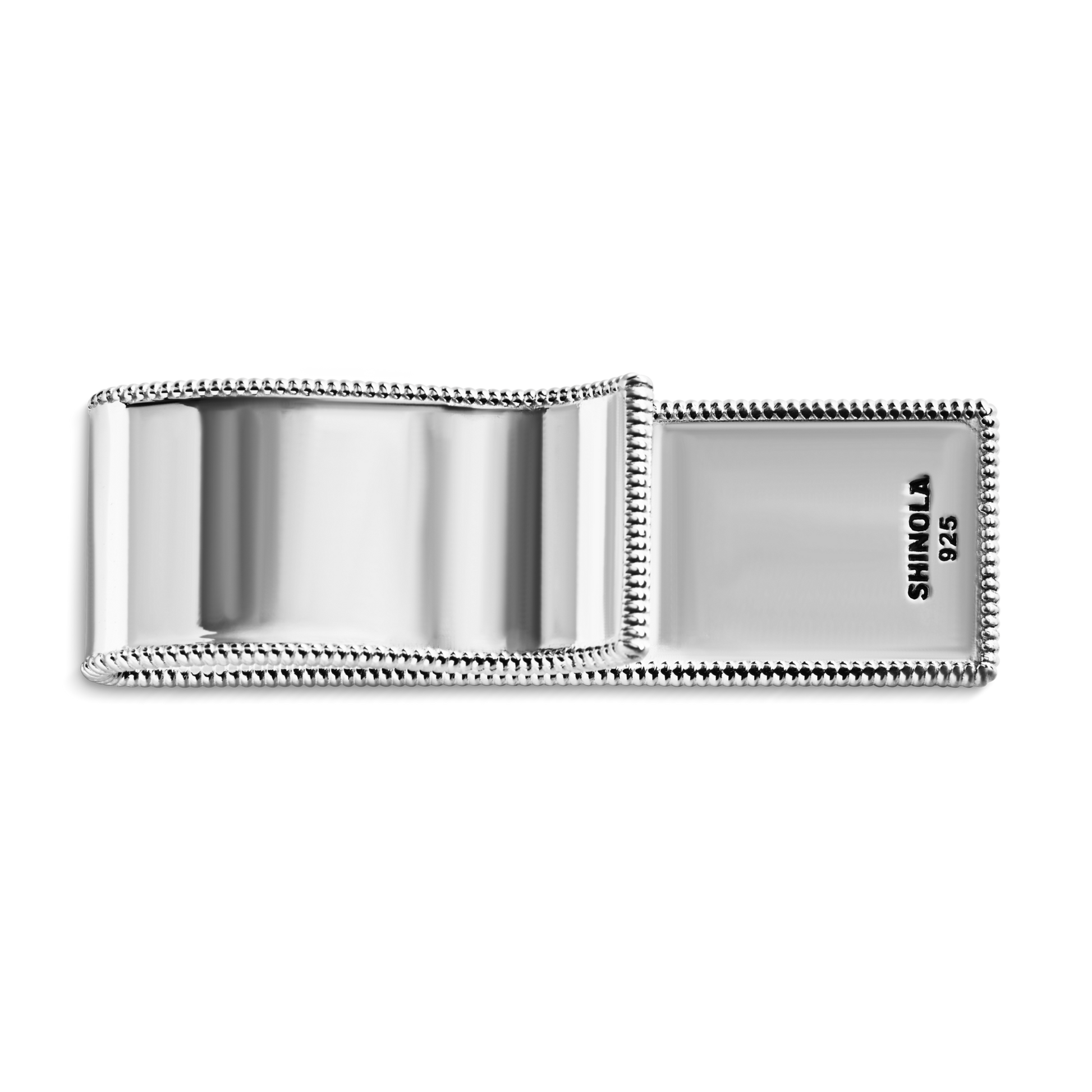 The Shinola Coin Edge Money Clip is crafted from polished sterling silver with a coin edge design, engraved with "Shinola" and "925" on the inside flap.