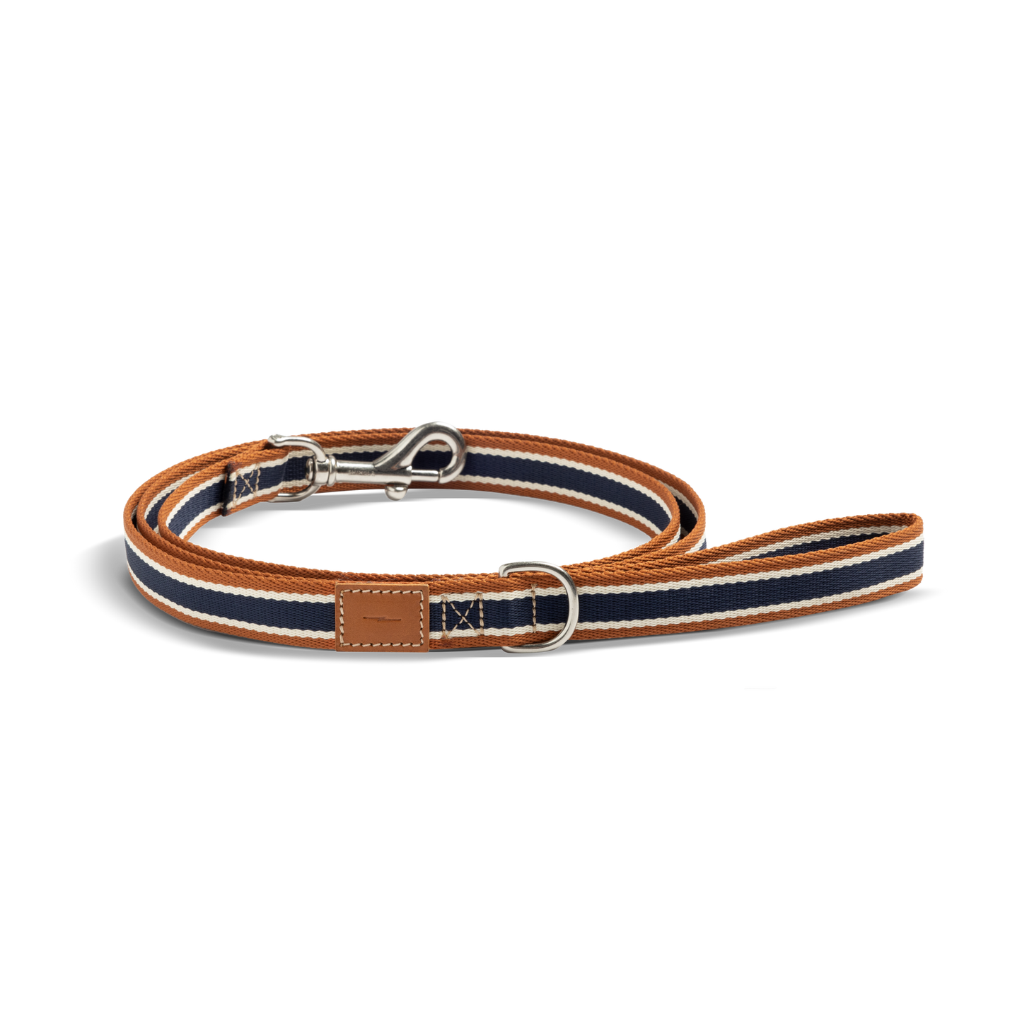 The Shinola Nylon Dog Leash - Brand Stripe features navy, white, and brown stripes, a silver clasp, D-ring, and stitched leather patch near the handle. Durable and stylish, it's shown coiled on a white background.