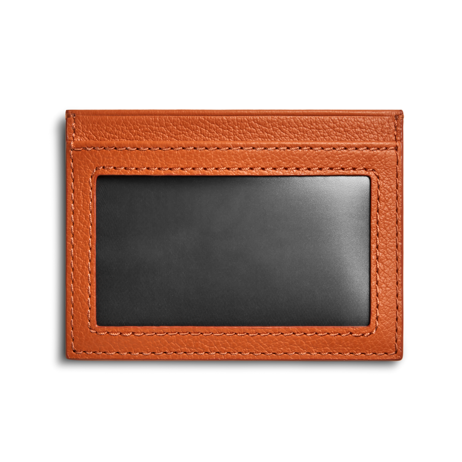 The Shinola Canfield ID Card Holder in Rust features a slim design with visible stitching, pebbled brown leather, and a transparent ID window, shown against a white background.