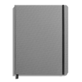 The Shinola Large Hard Grid Journal in Stone features a closed, gray linen cover with a black elastic band on the right edge and a black ribbon bookmark, all set against a white background.