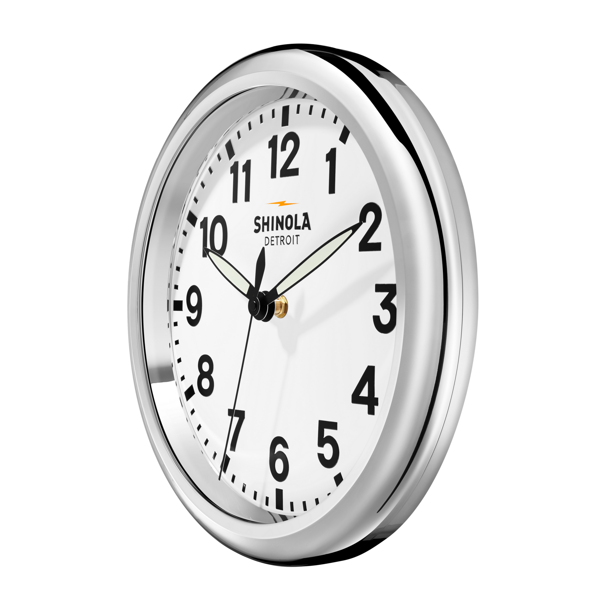A Shinola 14" Runwell Clock in white features a chrome casing, minimalist face with black numbers and hands showing 1:50, and "Shinola Detroit" branding, embodying the signature style of the collection.