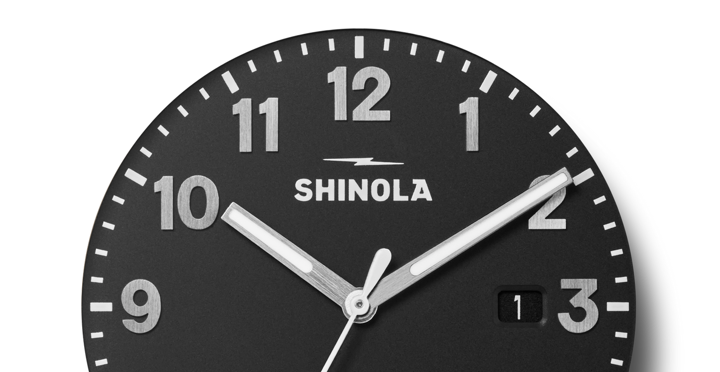 Close-up of the Shinola Detrola Watch - Black, featuring bold white numerals on a black dial with a small date window, reflecting durable construction and classic American design.