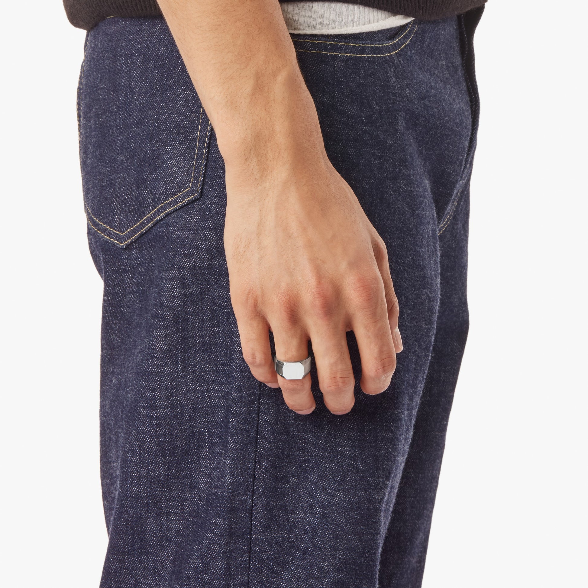 A person in dark blue jeans and a black shirt is shown from the waist down, wearing Shinola’s Octagonal Signet Ring – Sterling Silver on their middle finger, with their left hand at their side.