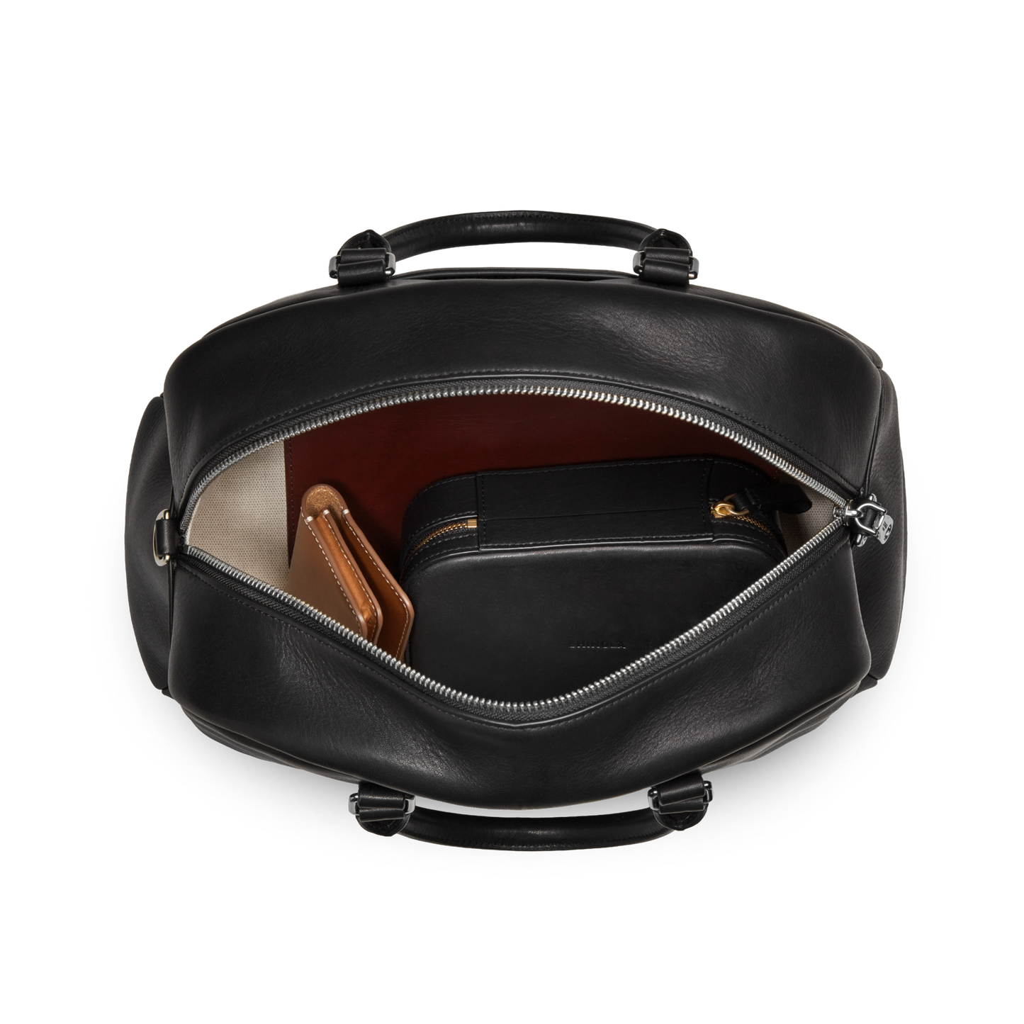 The Shinola Runwell Satchel - Black is unzipped to reveal a brown wallet and black pouch arranged on its light-colored lining.