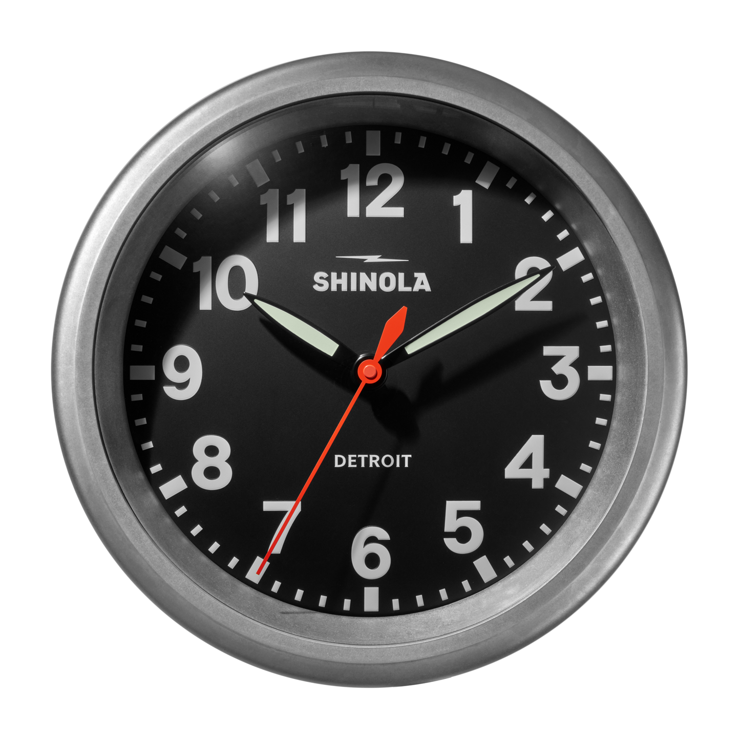 The 14" Runwell Clock by Shinola features a tumbled zinc casing, black face, white numerals, luminescent hour and minute hands, red second hand, displays 10:09:34, and showcases an industrial design.