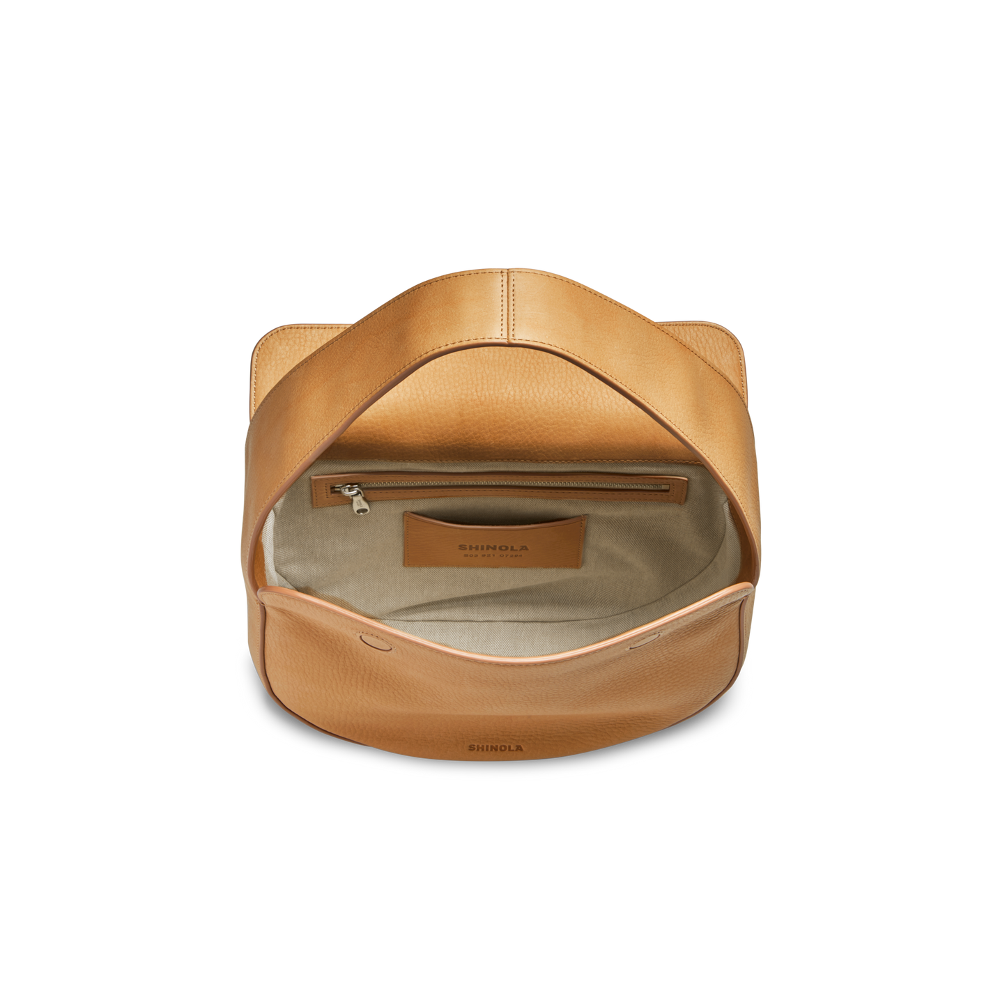 The Small Shoulder Bag - Honey by Shinola is shown from above on a white background. Crafted from tan natural grain leather, it features a flap opening to a beige fabric-lined interior with an inner zipper pocket and a Shinola leather logo patch.