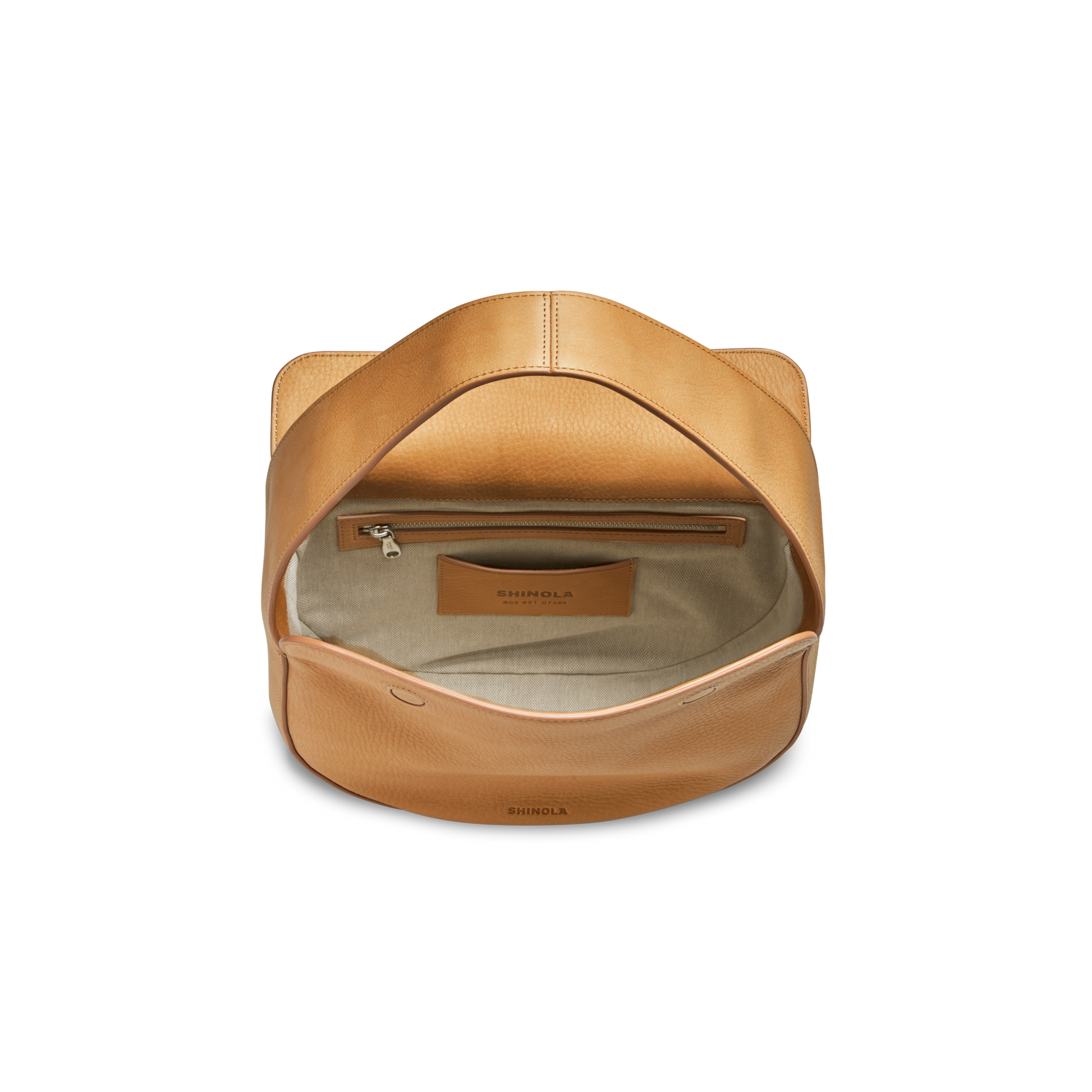 The Small Shoulder Bag - Honey by Shinola is shown from above on a white background. Crafted from tan natural grain leather, it features a flap opening to a beige fabric-lined interior with an inner zipper pocket and a Shinola leather logo patch.