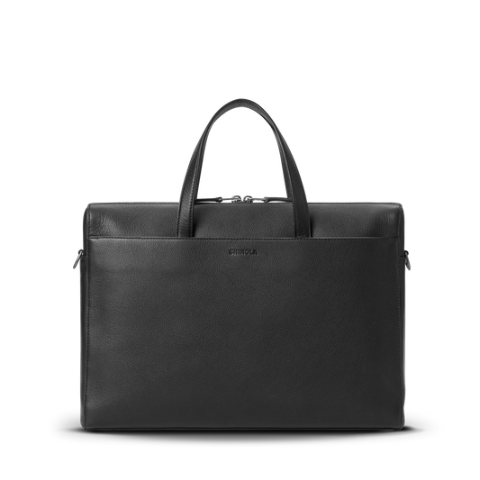 The Shinola Canfield Briefcase in black pebbled leather features dual handles, a front pocket, and a center embossed logo—ideal for modern commuters. Shown against a plain white background.