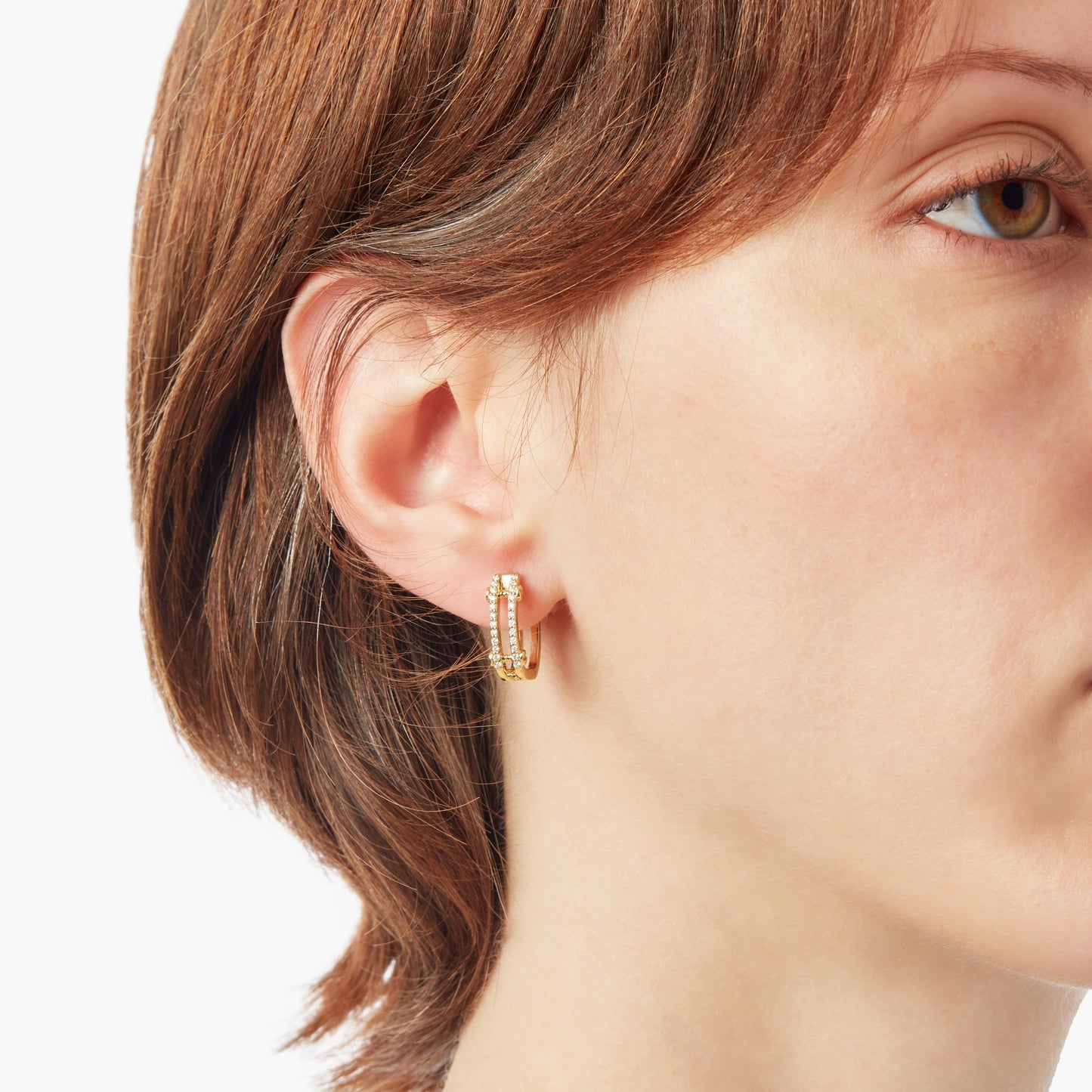 Close-up of a person with short brown hair wearing Shinola Diamond Pave Rivet Double Row Hoop Earrings in 14k yellow gold, shown in their left ear against a plain white background.