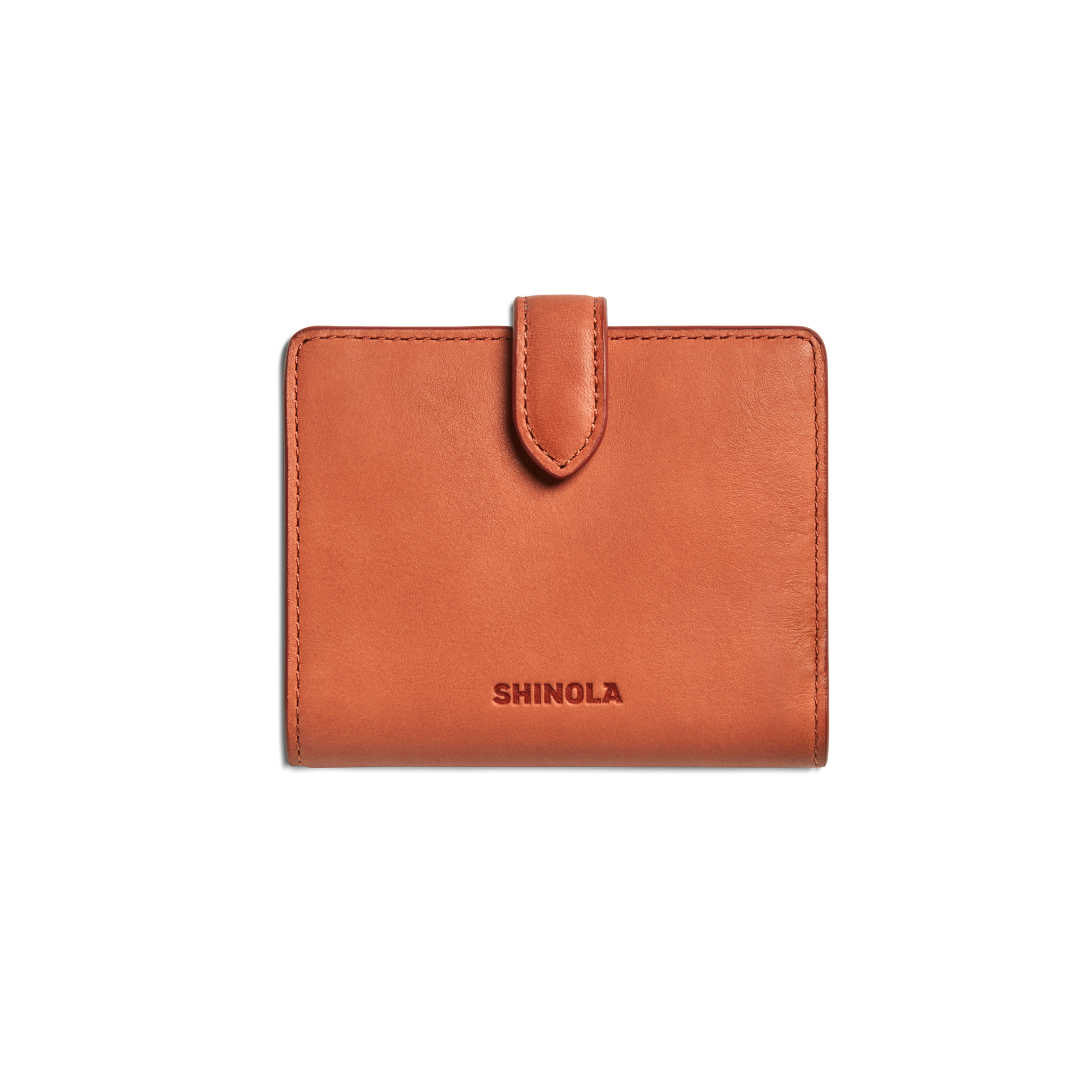 A compact wallet in rust natural leather with a snap tab closure and "Shinola" embossed on the front, displayed against a plain white background.