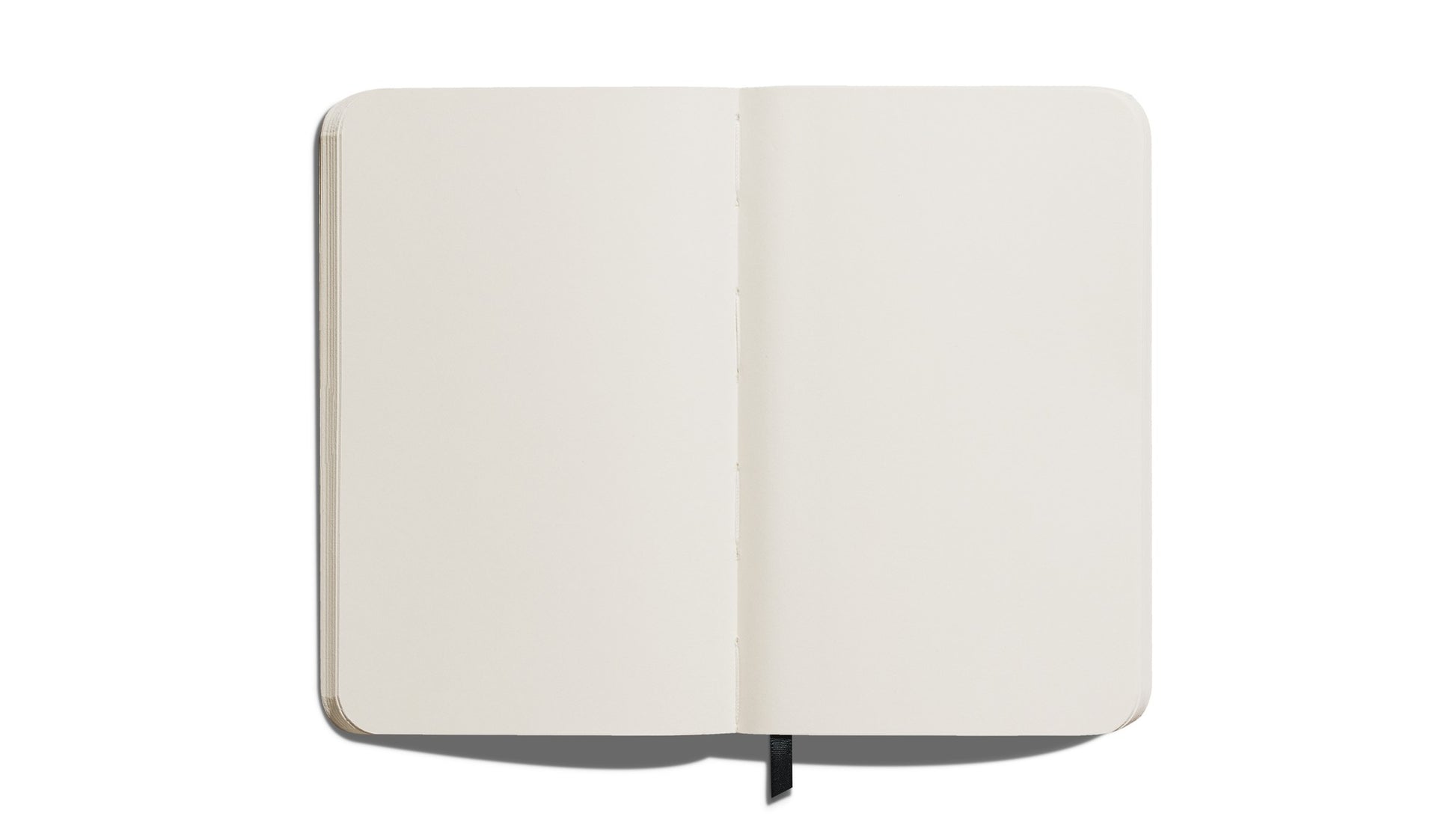 The Shinola Medium Hard Plain Journal in black features cream, acid-free pages and rounded corners. It lies flat with a black ribbon bookmark visible against a white background.