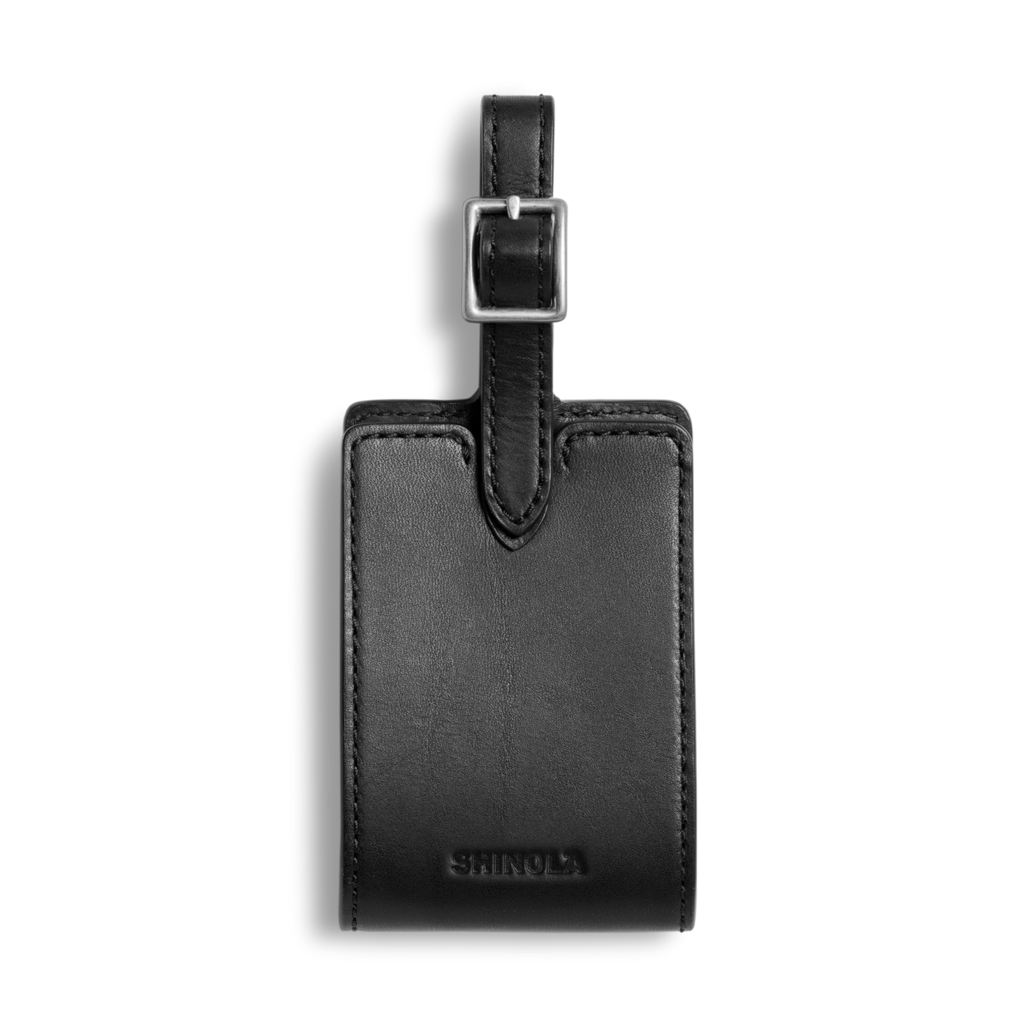 The Shinola Luggage Tag - Black, made from Italian Vachetta leather with a silver buckle and embossed branding, is shown on a white background. Personal monogramming is available.