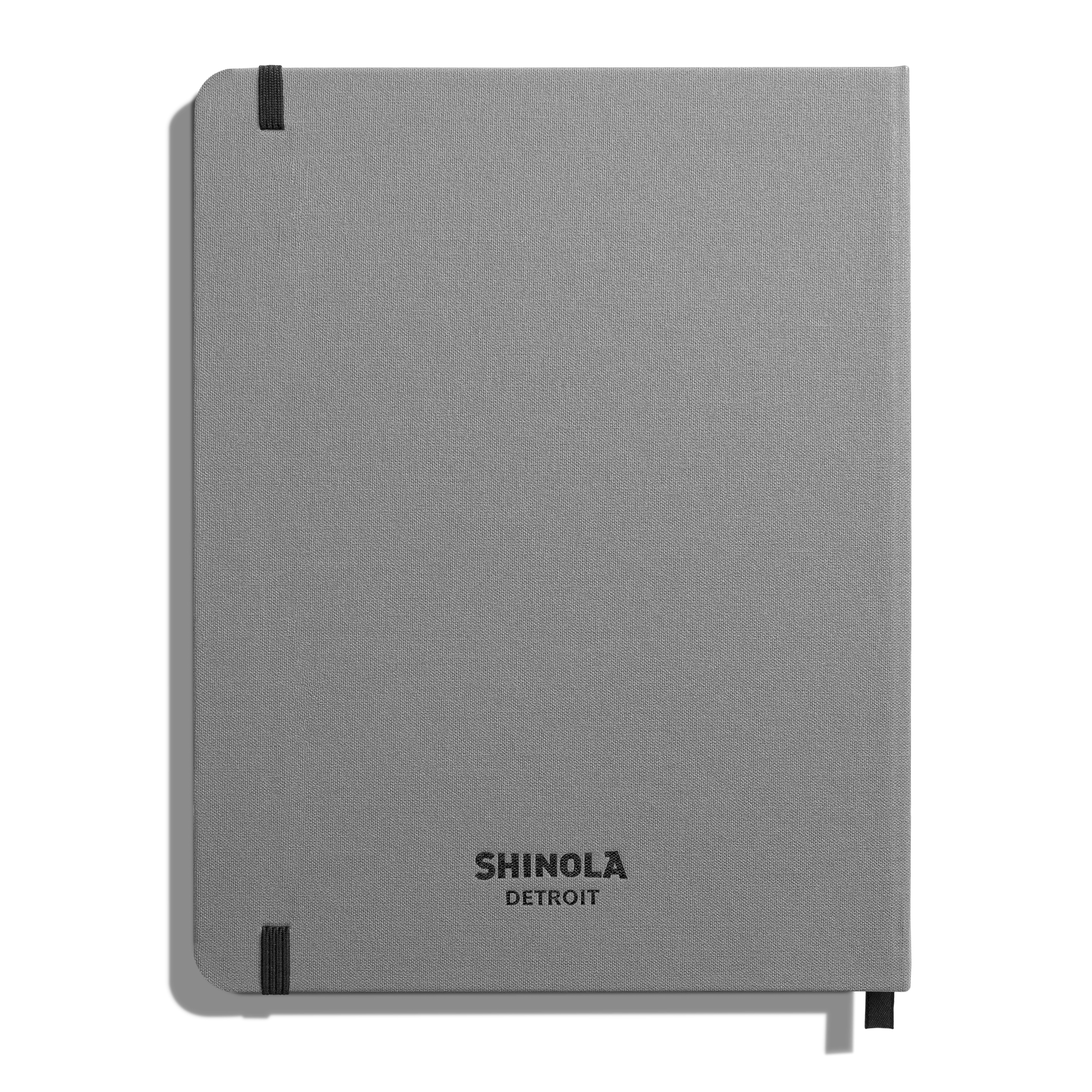A closed Large Hard Plain Journal - Stone by Shinola featuring rounded corners, black elastic band, smyth-sewn binding, and the Shinola logo centered at the bottom.