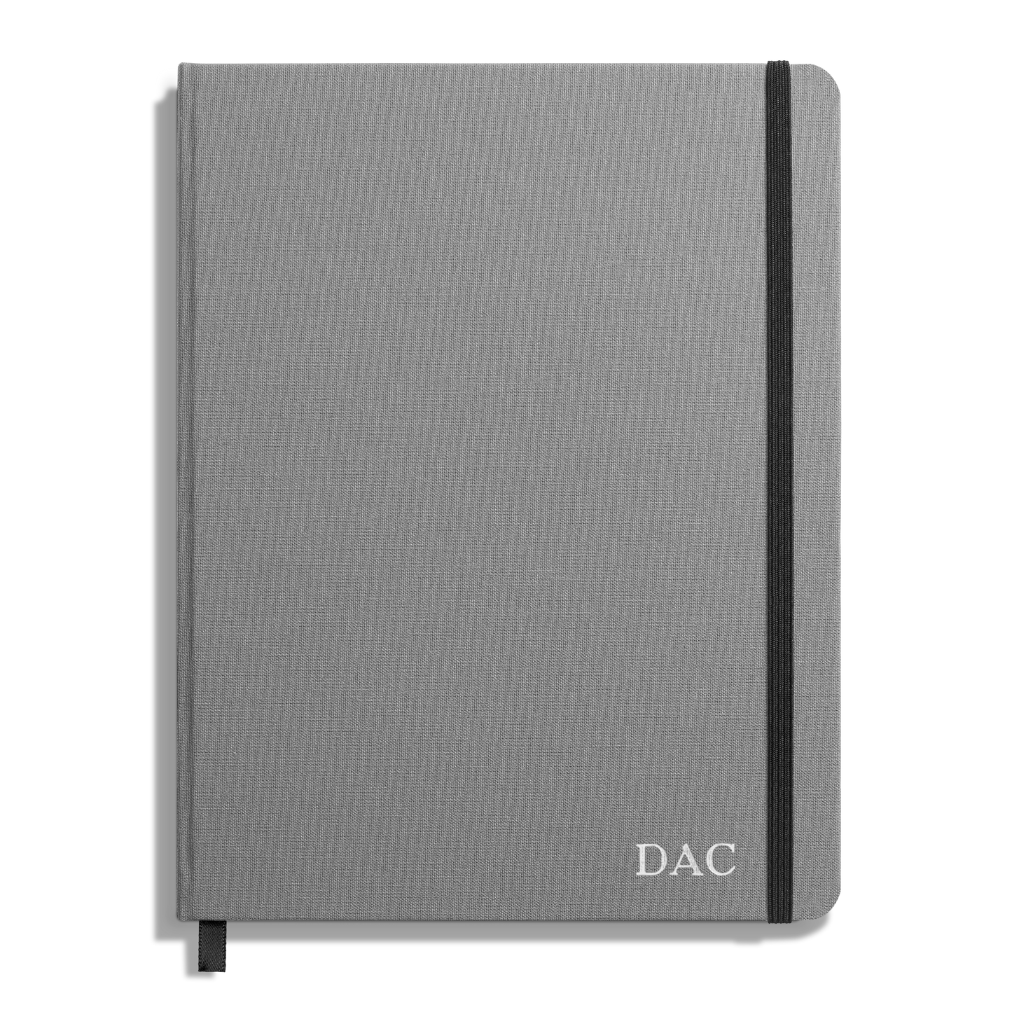The Shinola Large Hard Grid Journal - Stone features a gray hardcover with a black elastic band, black ribbon bookmark, and DAC initials in white on the bottom right corner, plus acid-free paper for long-lasting notes.