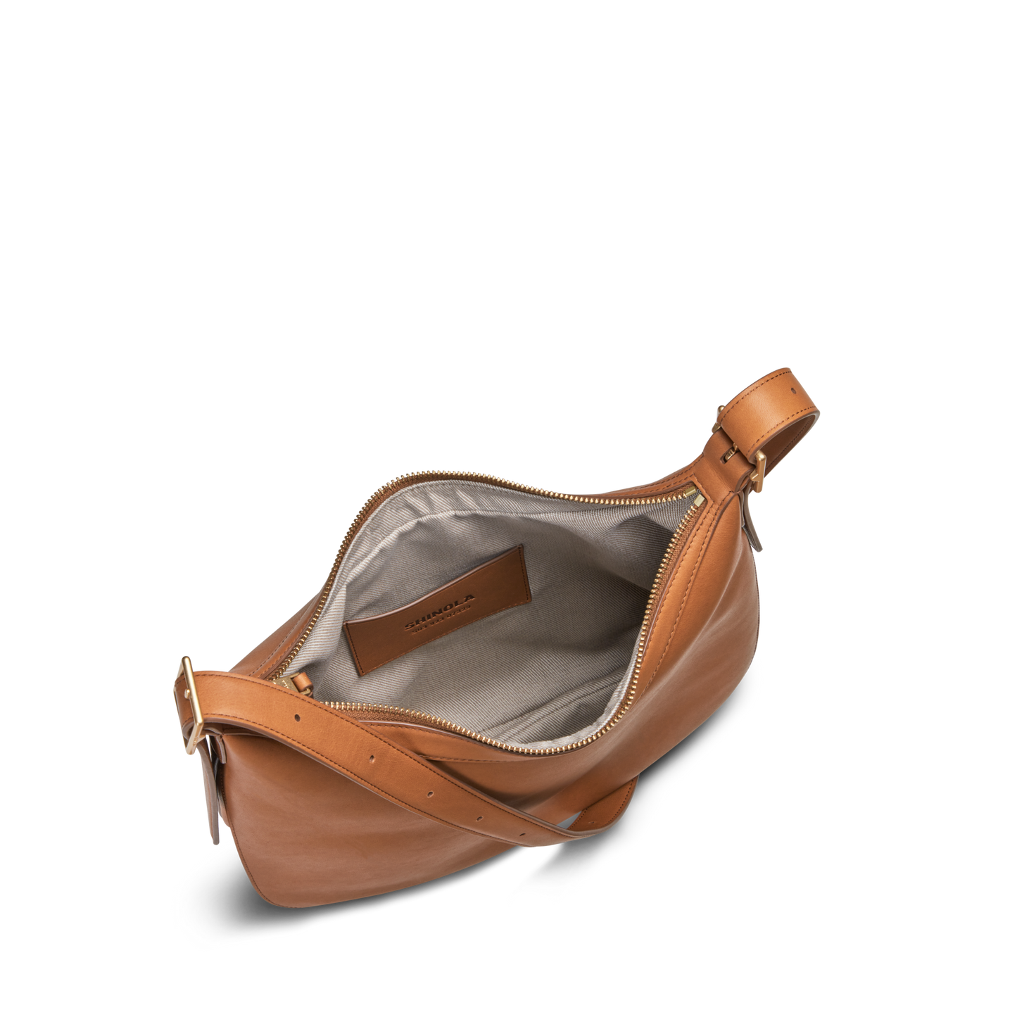 The Bixby Shoulder Bag - Tan by Shinola features tan natural leather, a gold zipper, an adjustable buckle strap, and opens to a light gray fabric interior with a small pocket accented by a brown leather label.