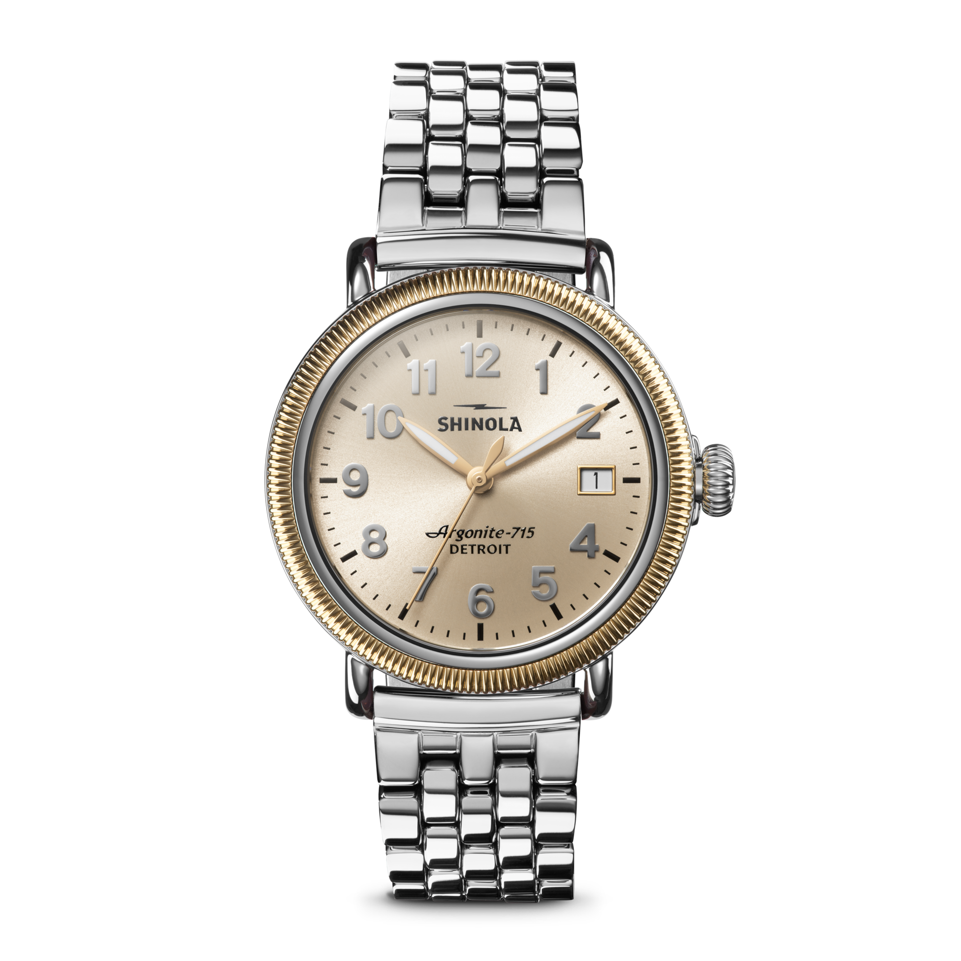 A Shinola Runwell Coin Edge Watch with a silver bracelet, gold bezel, cream dial, silver markers, and displaying 10:06. The watch face reads “Shinola Argonite-715 Detroit.”.