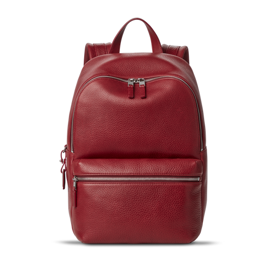 The Small Runwell Backpack - Ruby by Shinola, made from red Natural Grain Leather with a pebbled finish, features a front zippered pocket, main compartment, and top handle against a plain white background.