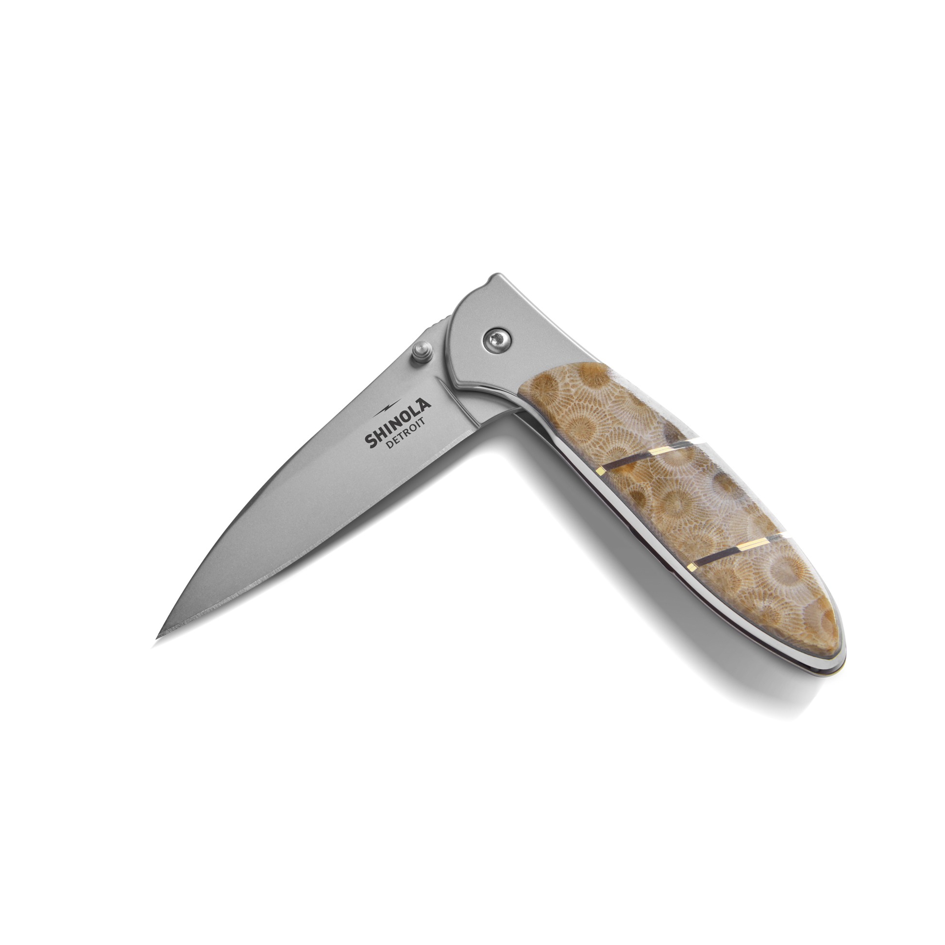 The Shinola + Kershaw Petoskey Stone Pocket Knife features a partially open silver blade engraved with "Shinola Detroit" and a handle inlaid with polished brown and beige Petoskey Stone.
