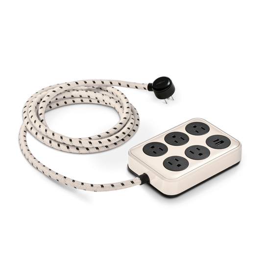The Shinola 5 Port Power Supply - Cream features a black and white braided cord, five round outlets, two USB A/C ports, and a rectangular base, all shown on a white background.