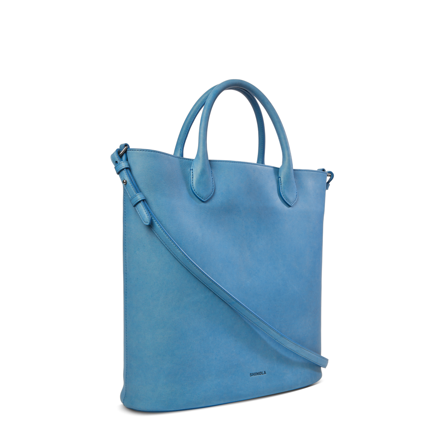 The Shinola 12 Hour Tote Bag - River is a stylish, light blue natural leather tote with short handles and a long adjustable strap—perfect for everyday use—shown against a plain white background.