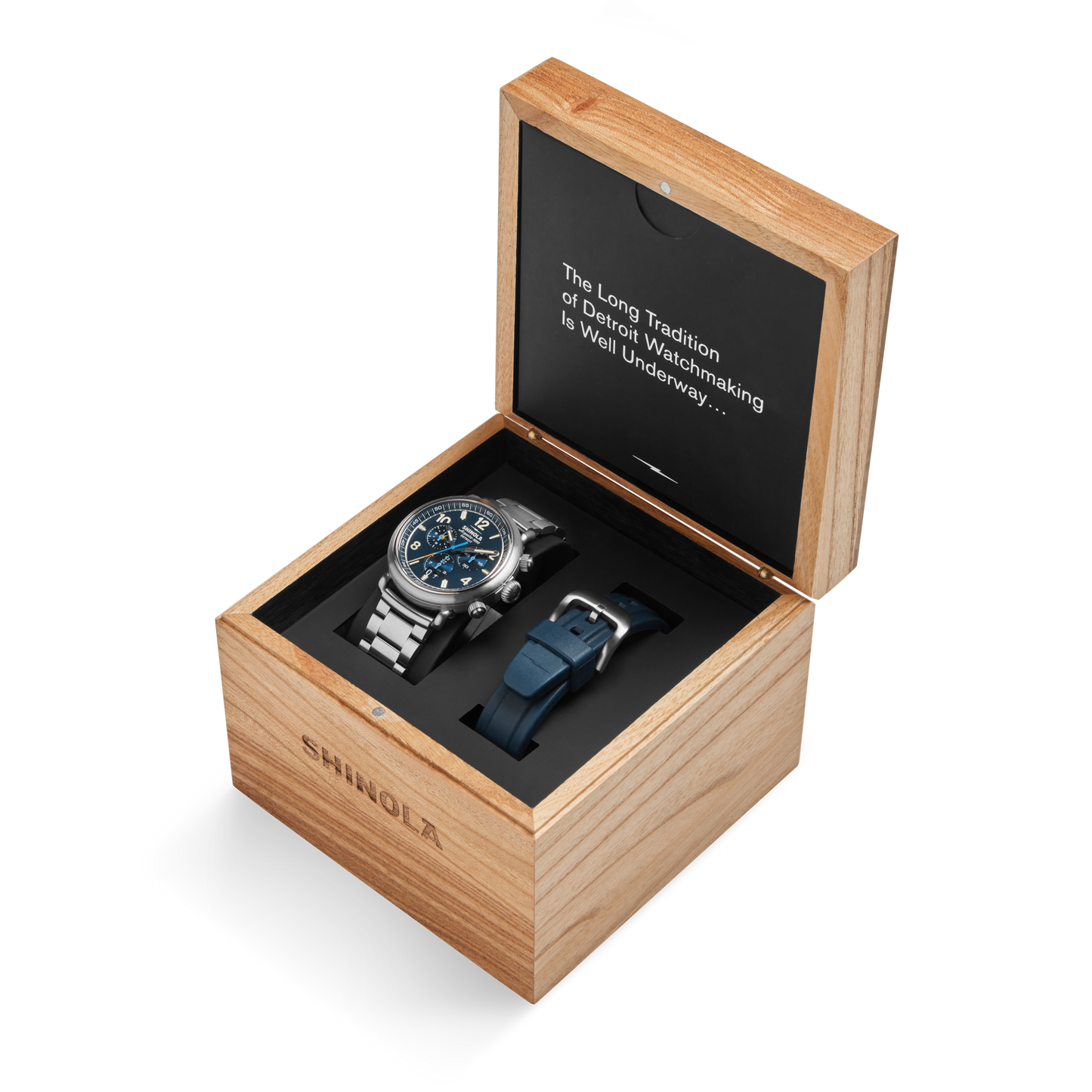The Shinola Runwell Chronograph West Wind Watch Gift Set features a 42mm silver wristwatch with a blue dial and metal band, displayed in an open wooden box with an extra blue strap. The inside lid reads, "The Long Tradition of Detroit Watchmaking is Well Underway,….