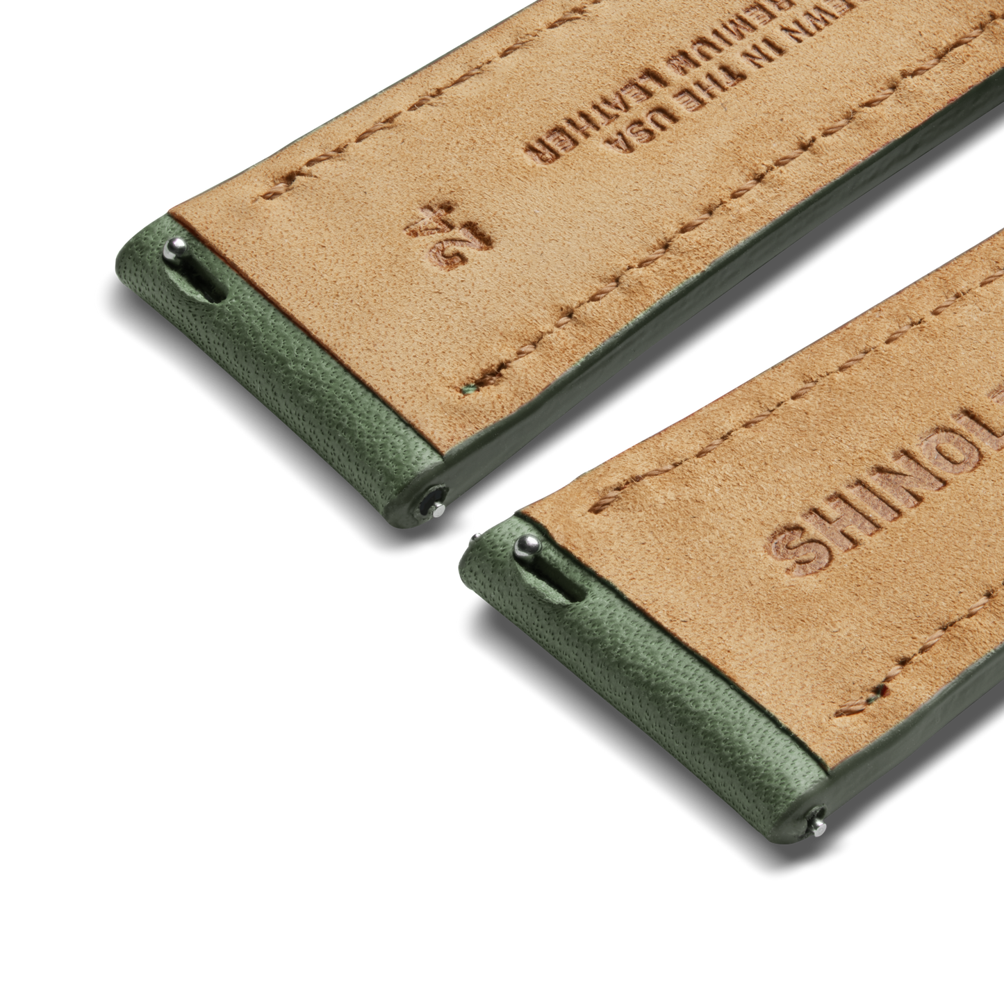 Close-up of two Shinola 24mm green leather watch straps diagonally placed, showing detailed stitching, metal spring bars, and "genuine leather" USA stamp—ideal for the Runwell Sport 48mm.