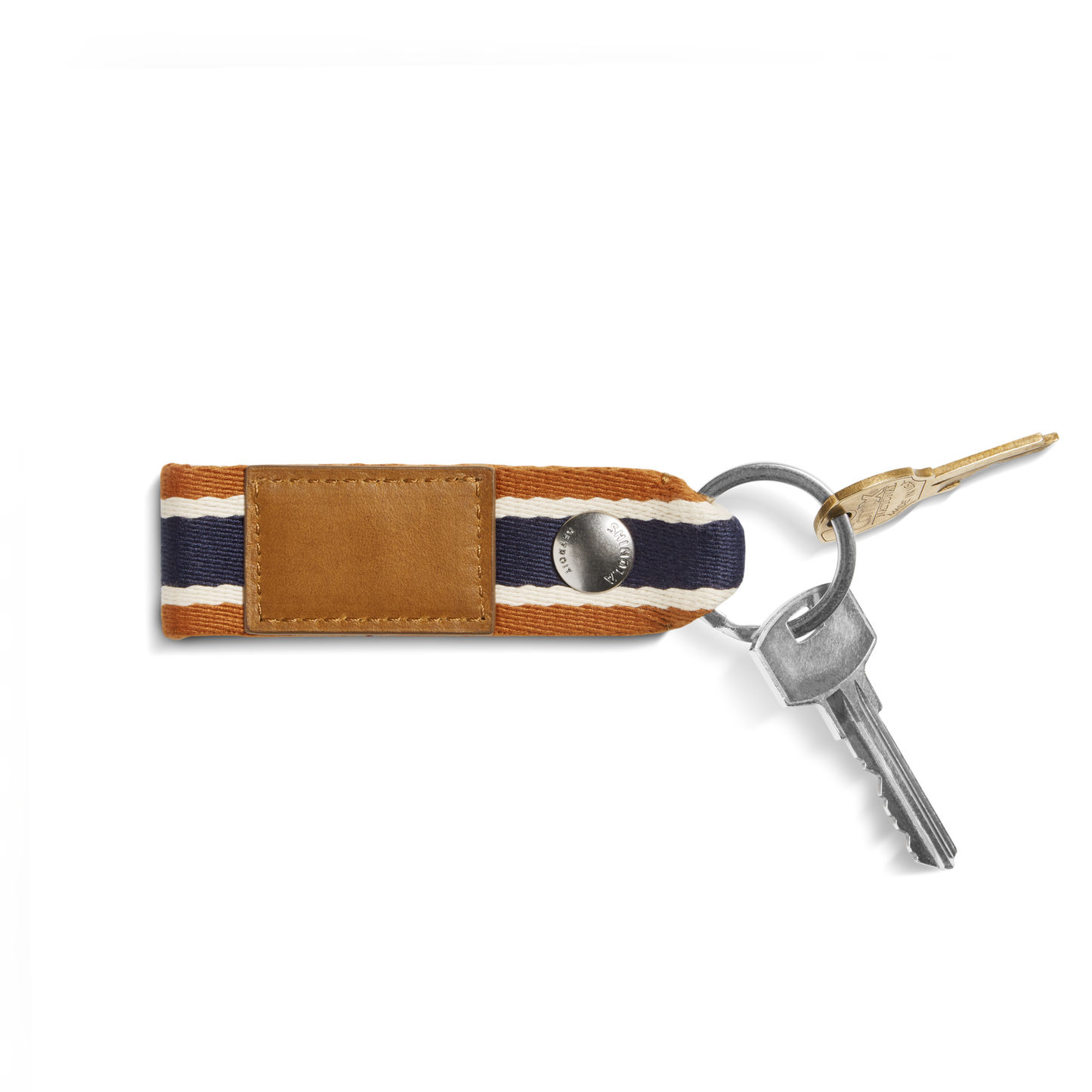A Shinola Webbing Keychain - Brand Stripe / Tan with a brown leather and striped fabric strap holds two silver keys and one gold key, set against a white background.