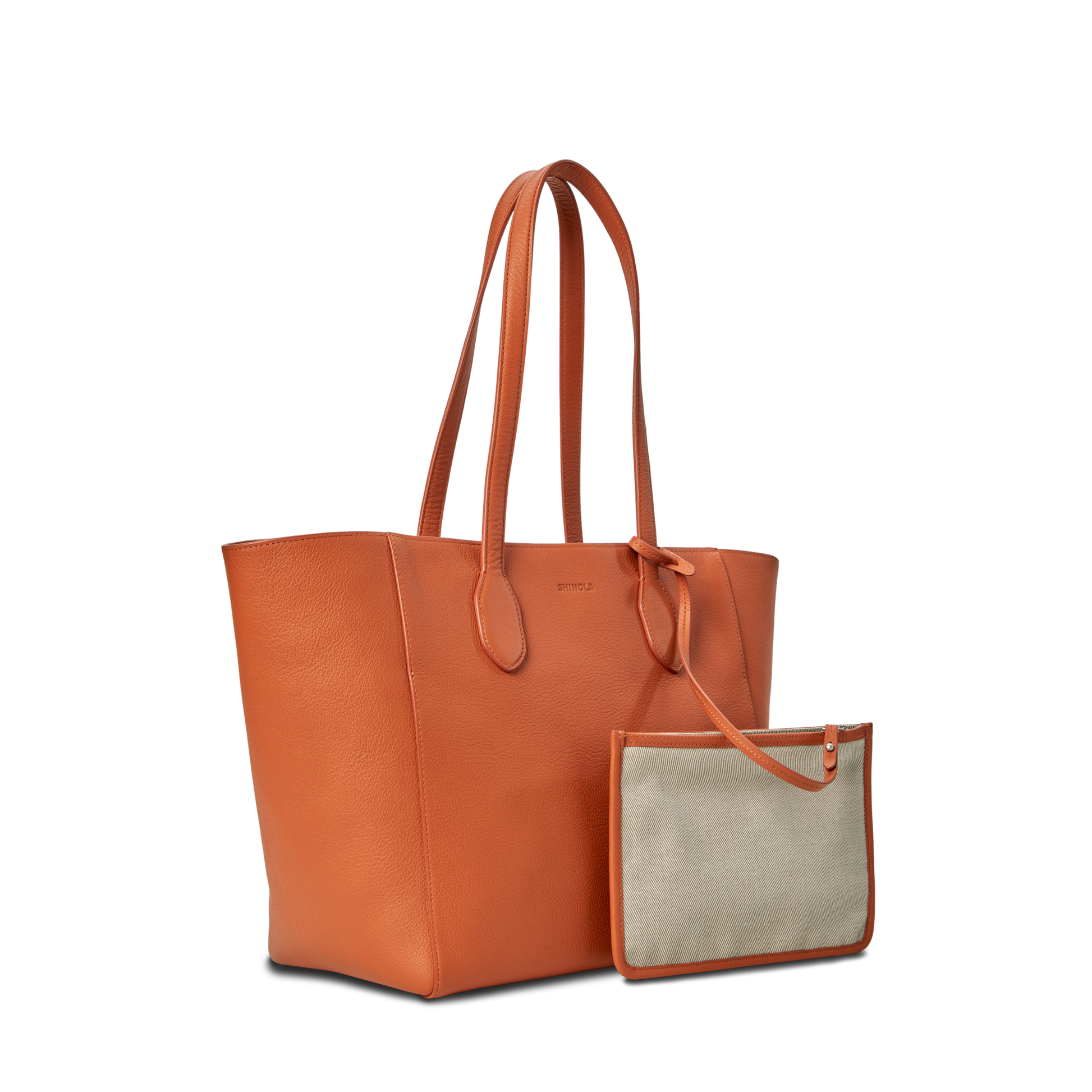 The Shinola Runabout Tote Bag in rust, featuring orange pebbled leather and two handles, is displayed beside a smaller beige and orange zipper pouch, both set against a plain white background.