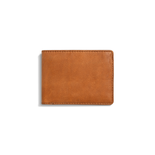 The Shinola Slim Bifold Wallet - Tan is shown closed against a white background, featuring premium light brown leather, visible edge stitching, and a simple, classic design.