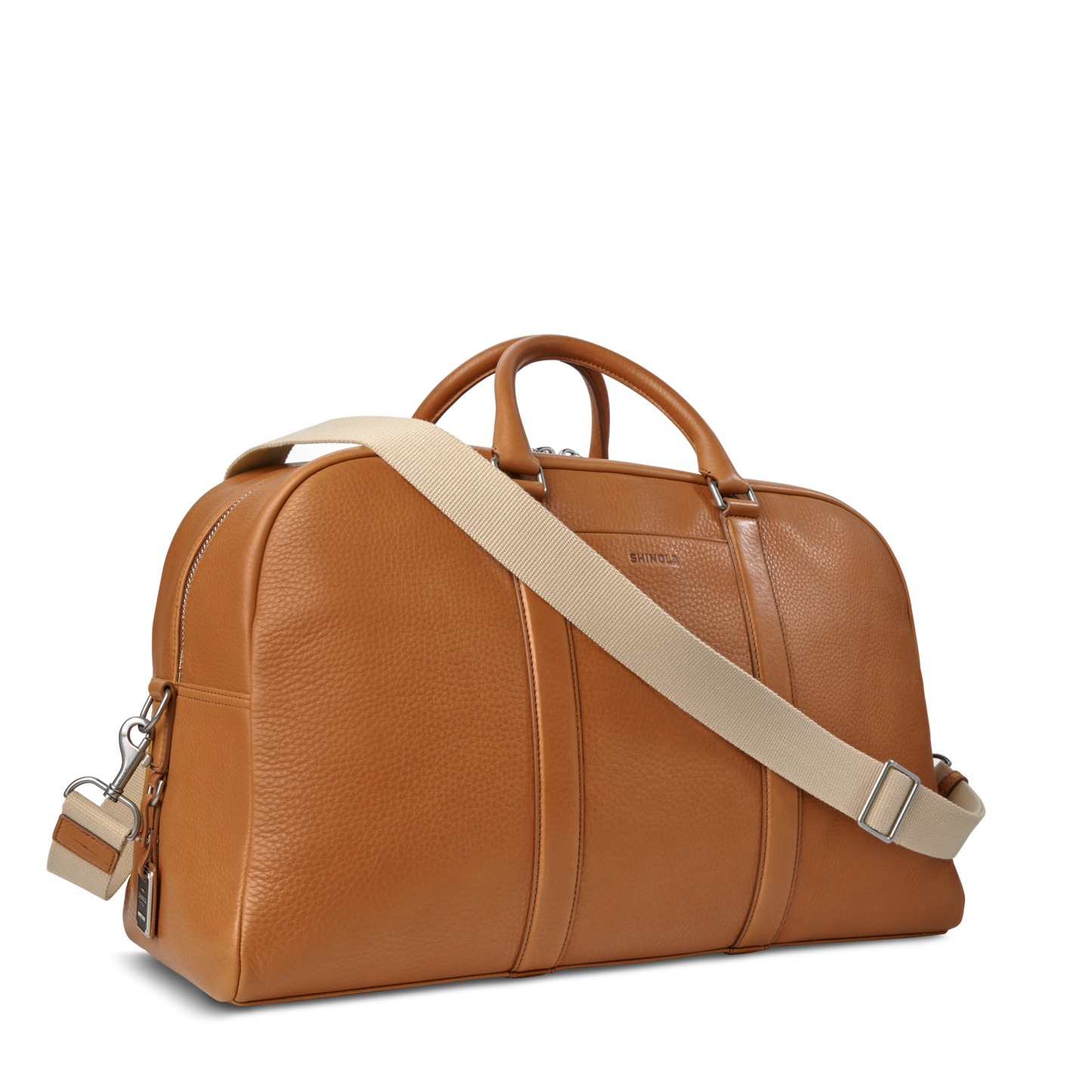 The Shinola Runwell Duffle Bag in tan features two handles, a beige adjustable shoulder strap, silver hardware, and a textured finish. This stylish leather travel bag is displayed against a plain white background.