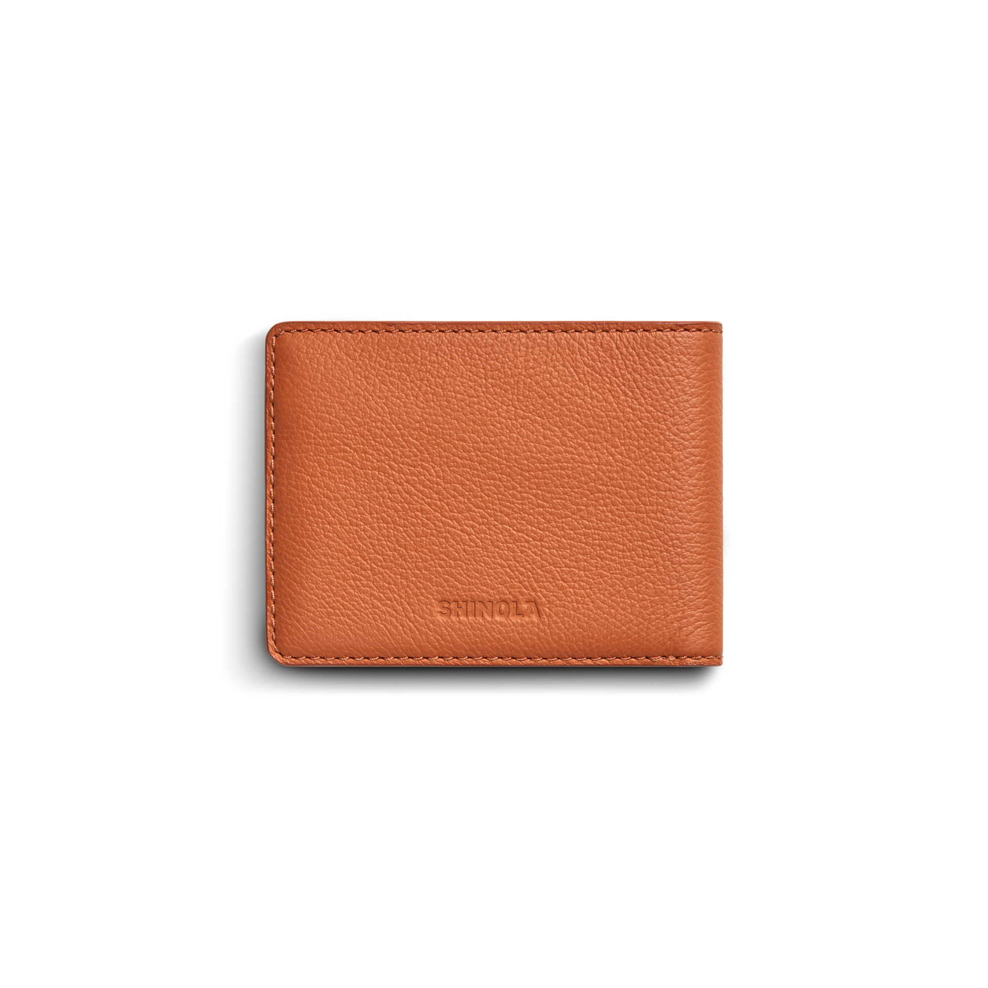 A closed Shinola Canfield ID Bifold wallet in rust-colored pebbled leather with a textured surface, stitched edges, and subtle brand embossing is shown against a white background.